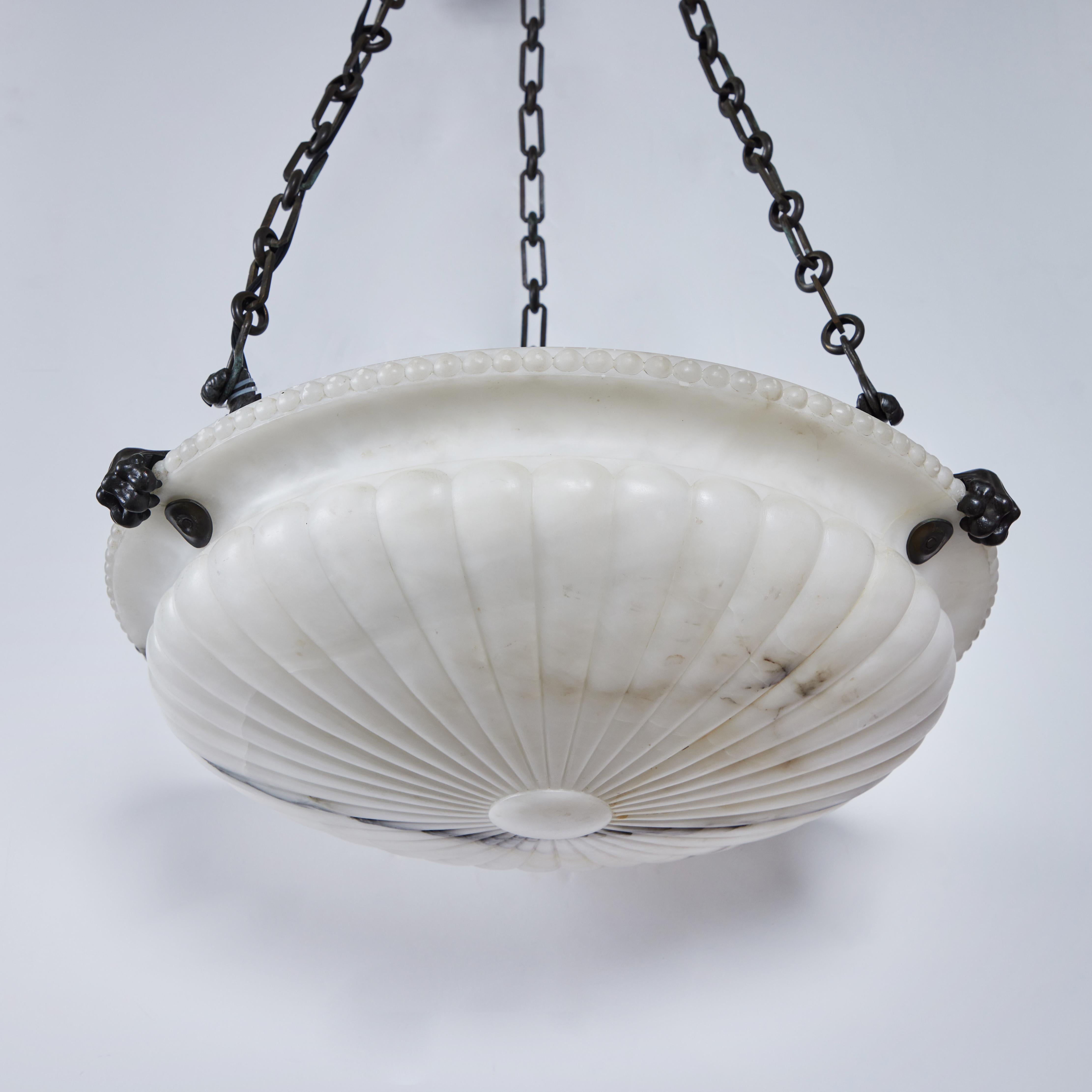 Beautifully hand-carved alabaster chandelier with the classic circular flared design. Held by 3 claws, chains and acanthus leaf canopy.  
