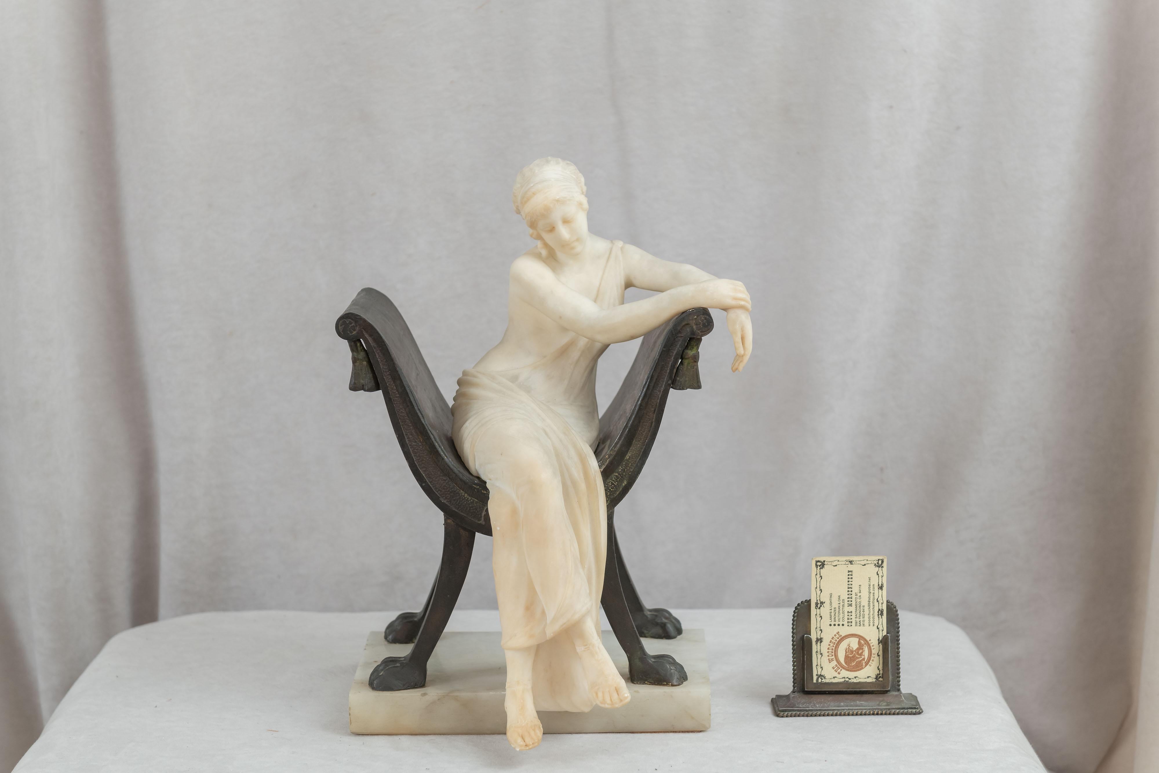 This most impressive example of what an artist can do with 2 mediums, is all here. The young lady is delicately hand carved in alabaster and showing off the artist's ability to create a very life-like figure. Seated on a bronze chair, the sculpture