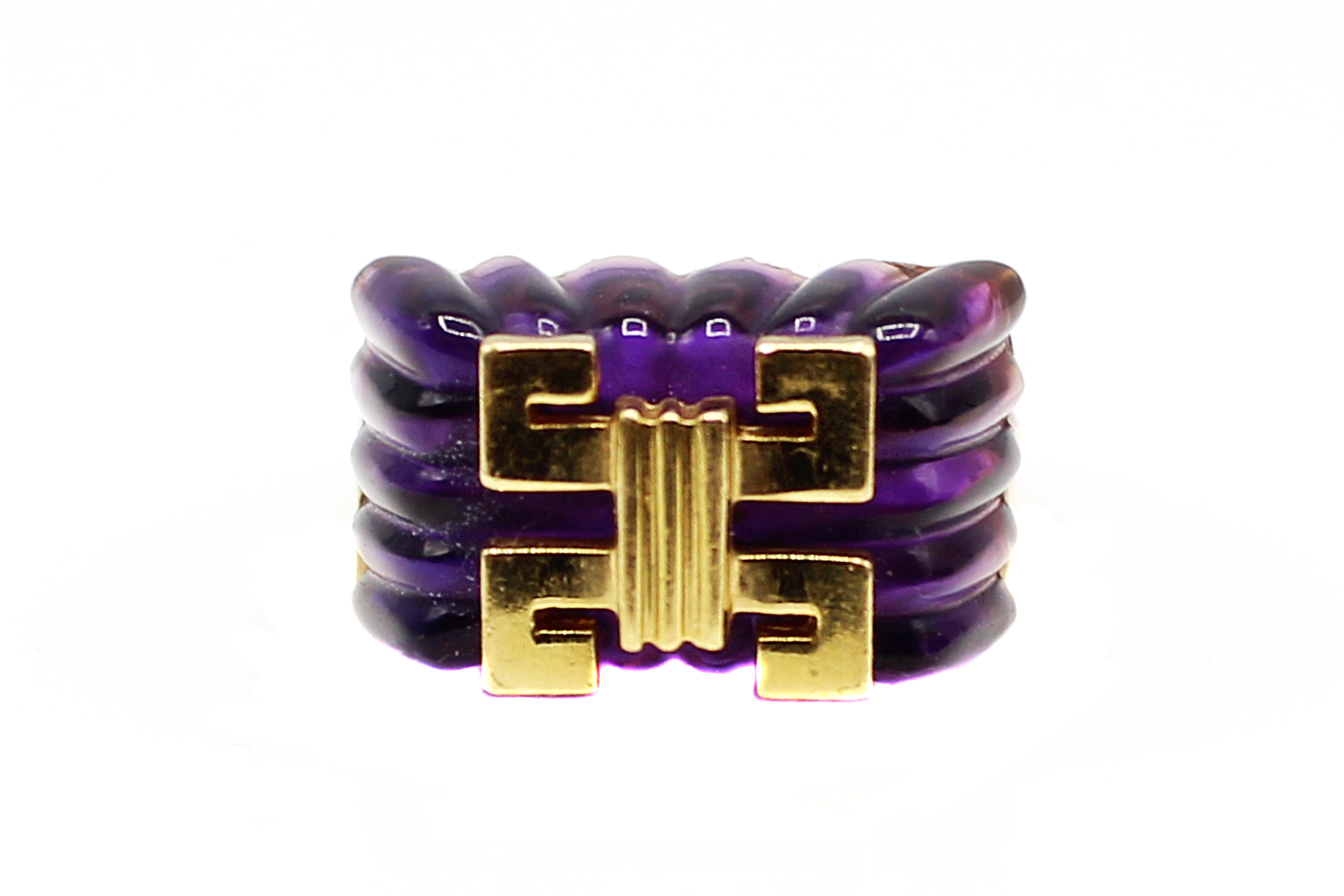 Bold and well handcrafted ring from the 1980s, showcases a deep violet carved Amethyst, accented with yellow gold geometric design elements. Amethysts with this kind of deep purple color saturation were mostly mined in Siberia. The amazing design