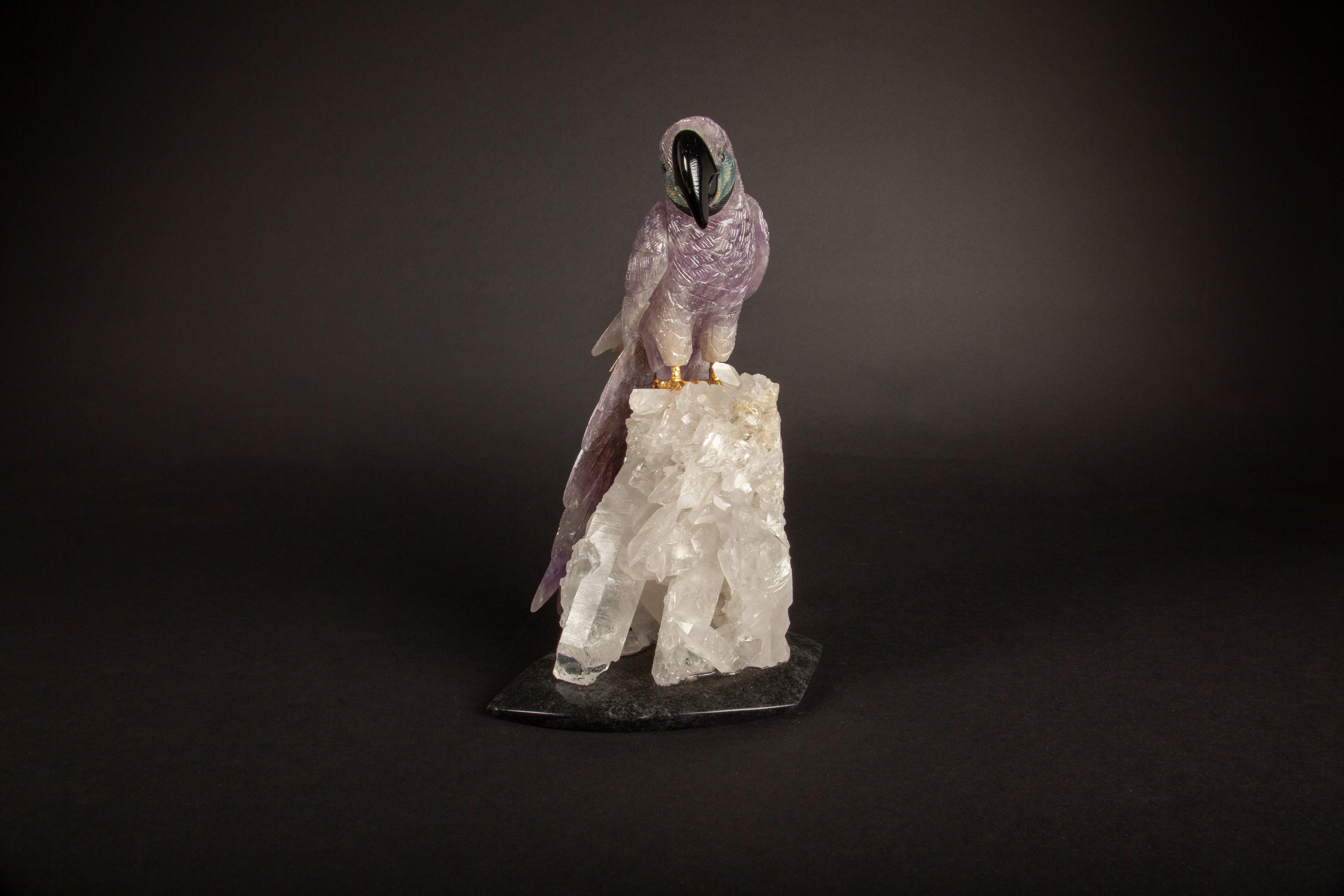 This exquisite 10.5-inch high carved vibrant amethyst parrot, meticulously handcrafted in Argentina, presents a stunning depiction of artisanal craftsmanship. Perched atop a rock crystal cluster, the sculpture captures the essence of natural beauty