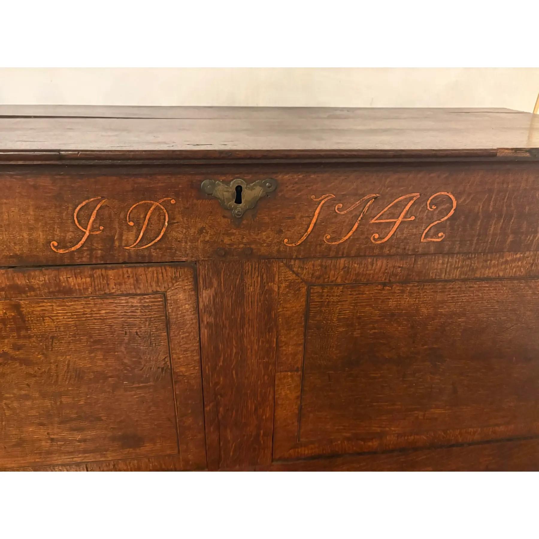Questa cassapanca in quercia intagliata e datata del XVIII secolo conserva la sua superficie antica con una patina calda.  Davvero unica nel suo genere, la parte anteriore è decorata con le iniziali intagliate I.D. e la data 1742.  Include i primi
