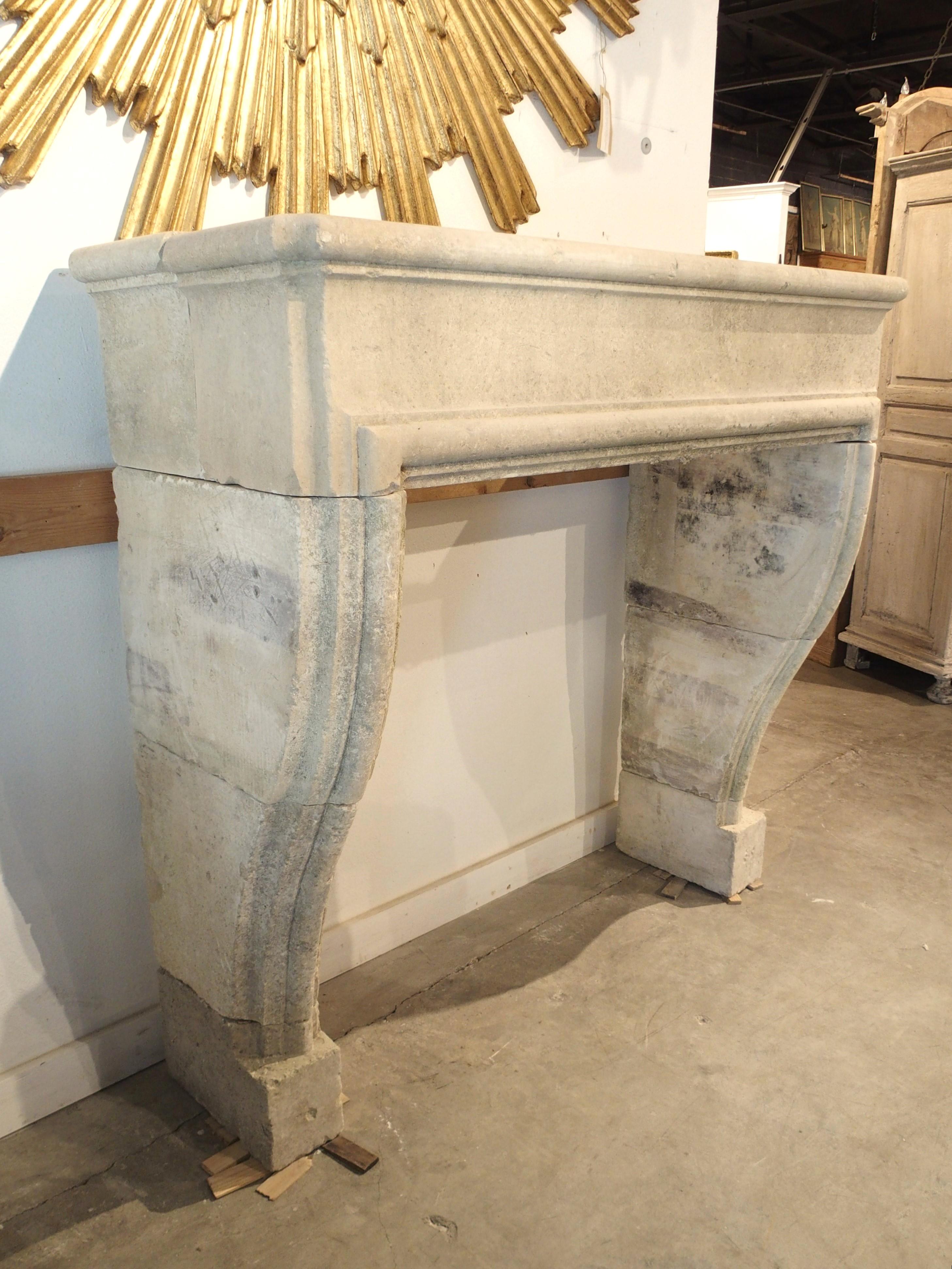 From Southern Italy, this elegant fireplace mantel has been hand-carved from nine pieces of limestone. The cream-colored stone has developed a nice black and gray patina and was intentionally distressed to give the appearance of antiquity. A