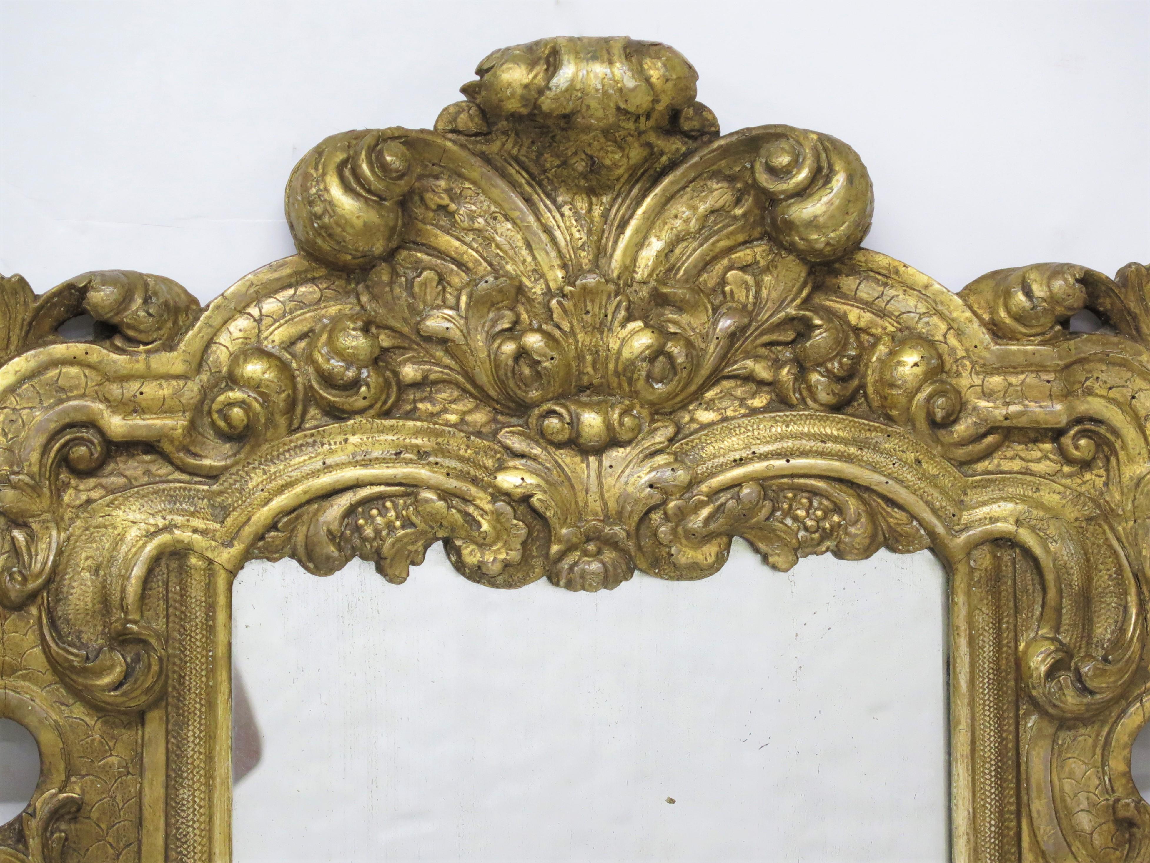 an Italian looking glass / mirror, carved and gilded, with scrolled acanthus leaves and scales. Baroque, 18th century, Italy