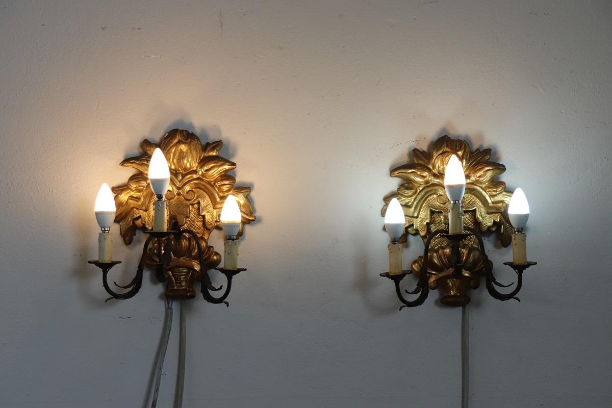 Lovely pair of sconces in carved and gilded fir wood. The gilding is made of precious gold leaf. Equipped with three bulbs each. Presence of some signs of the passage of time in the gilding.