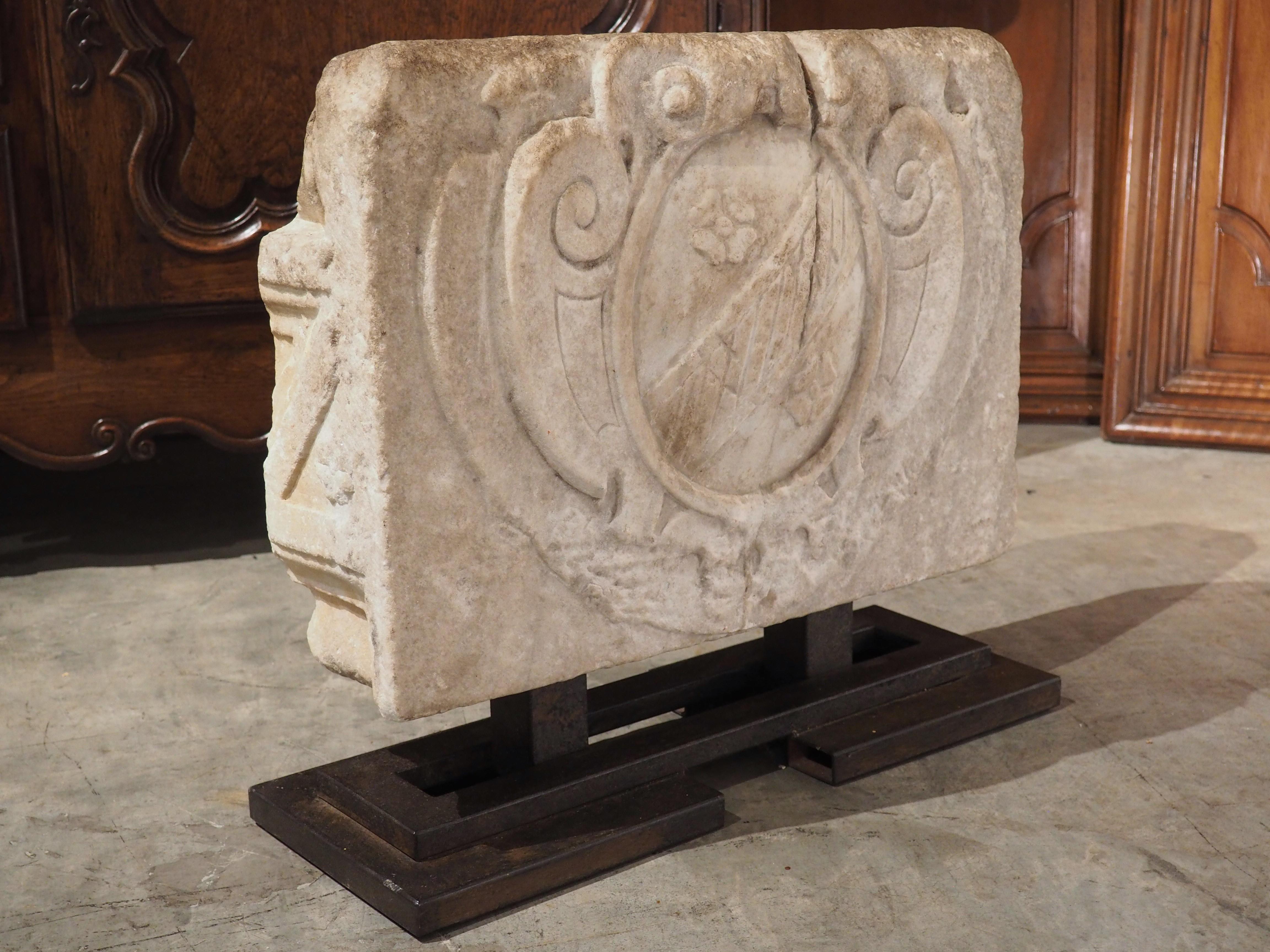 The carvings of this marble stemma cartouche dates to the 1500’s. Hand-carved in Tuscany, Italy, the marble was mounted onto a geometrically shaped iron stand within the last century.

Stemmas can be traced back to ancient Rome when genealogical