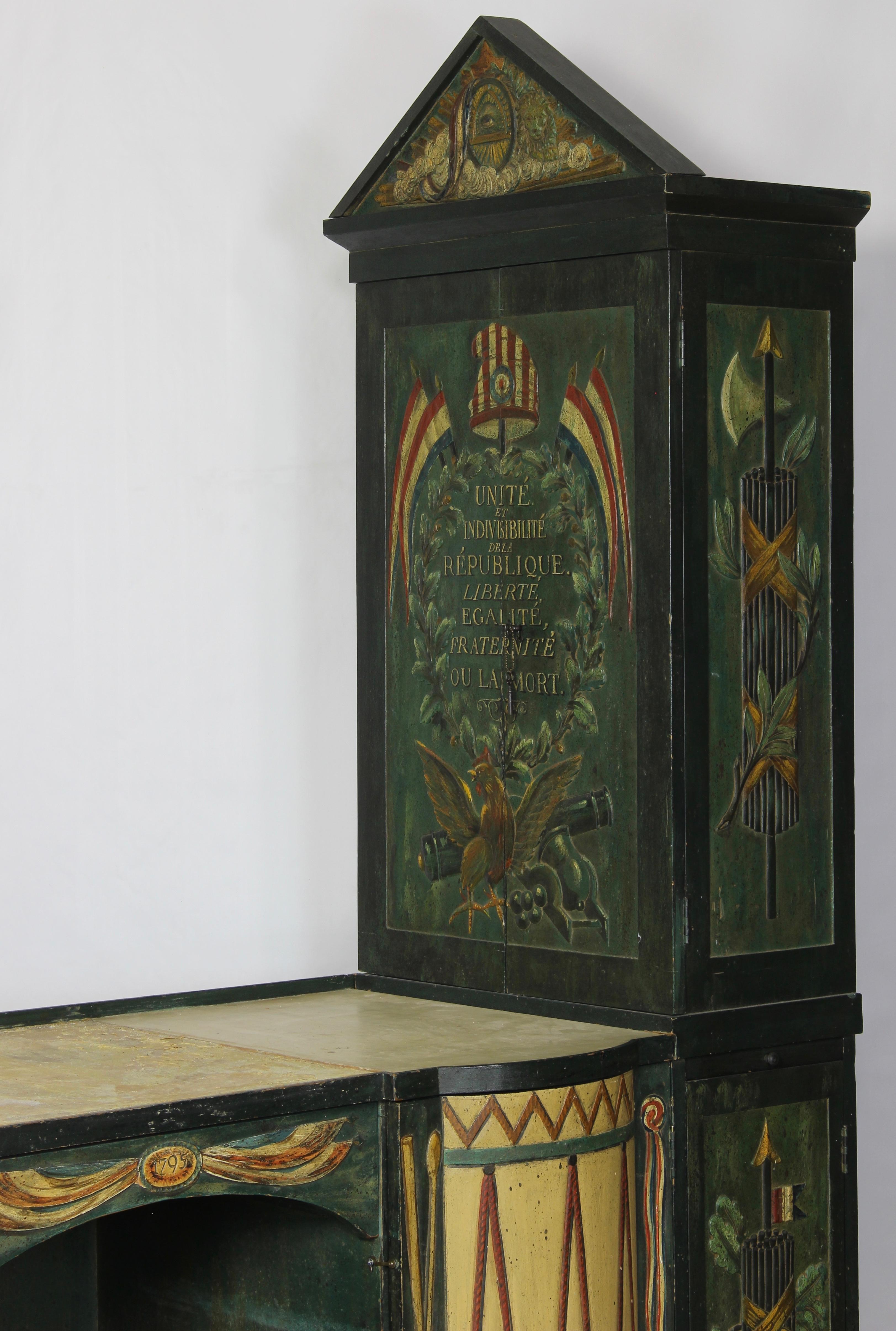 A charming and unusual early 20th century heavily carved and paint decorated desk commemorating the signing of the French constitution in 1795 complete with all the symbols of the French republic. The desk doors concealing shelves and drawers are