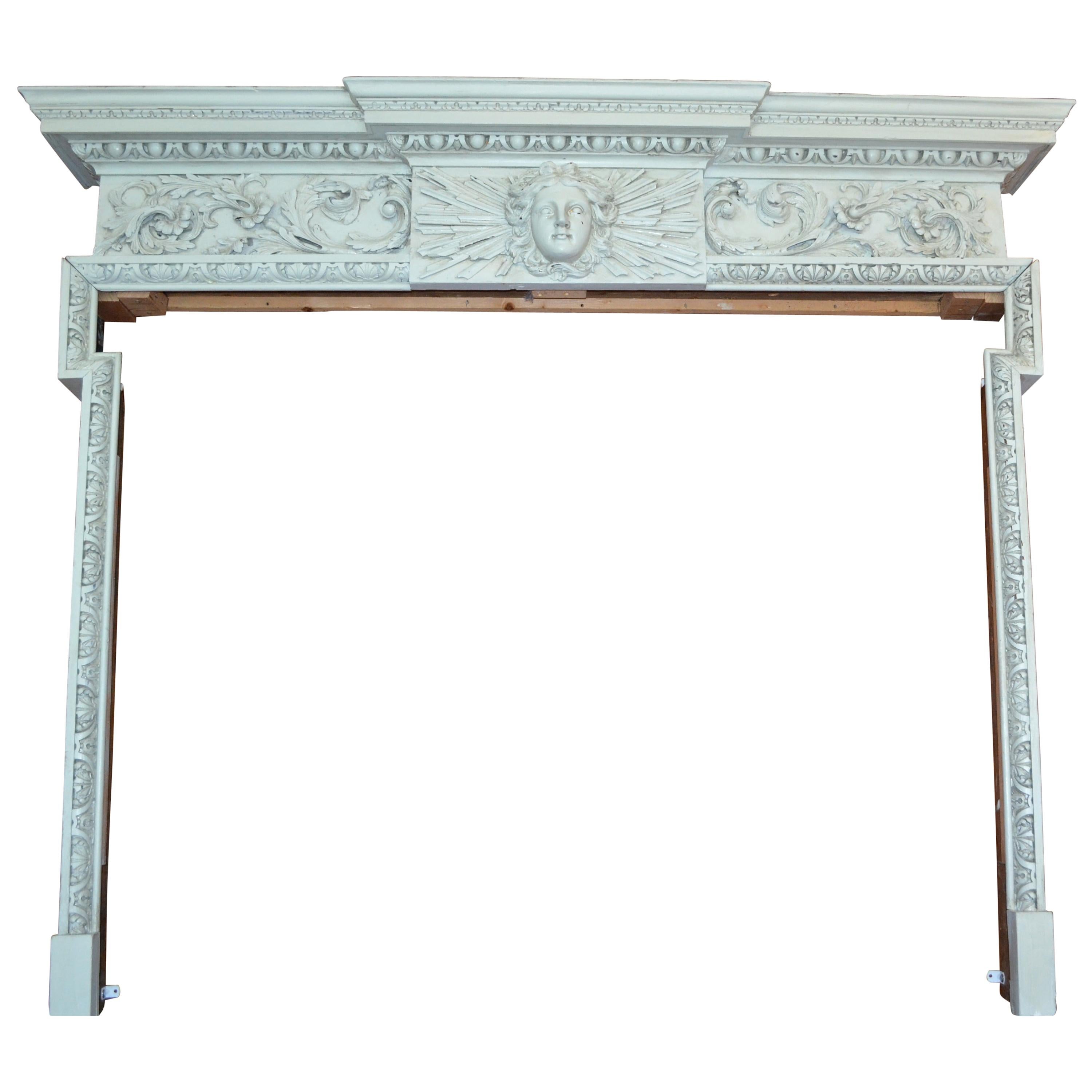 A painted pinewood id 18 century fireplace or chimneypiece surround with deep finely carved cushion frieze and a dramatic Louis XIV sunburst at the centre of frieze.

