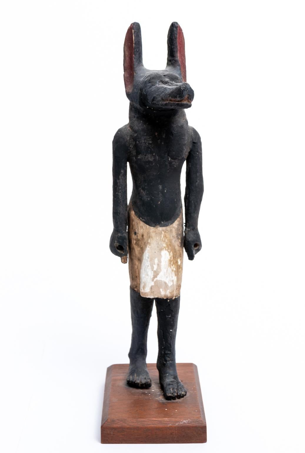 Circa 500 BC carved and painted Cedarwood Anubis statue crafted around the Late Period of Ancient Egyptian history on a later stand. The statue depicts the Ancient Egyptian God of Embalming, Mummification, and the Afterlife in a contrapposto or