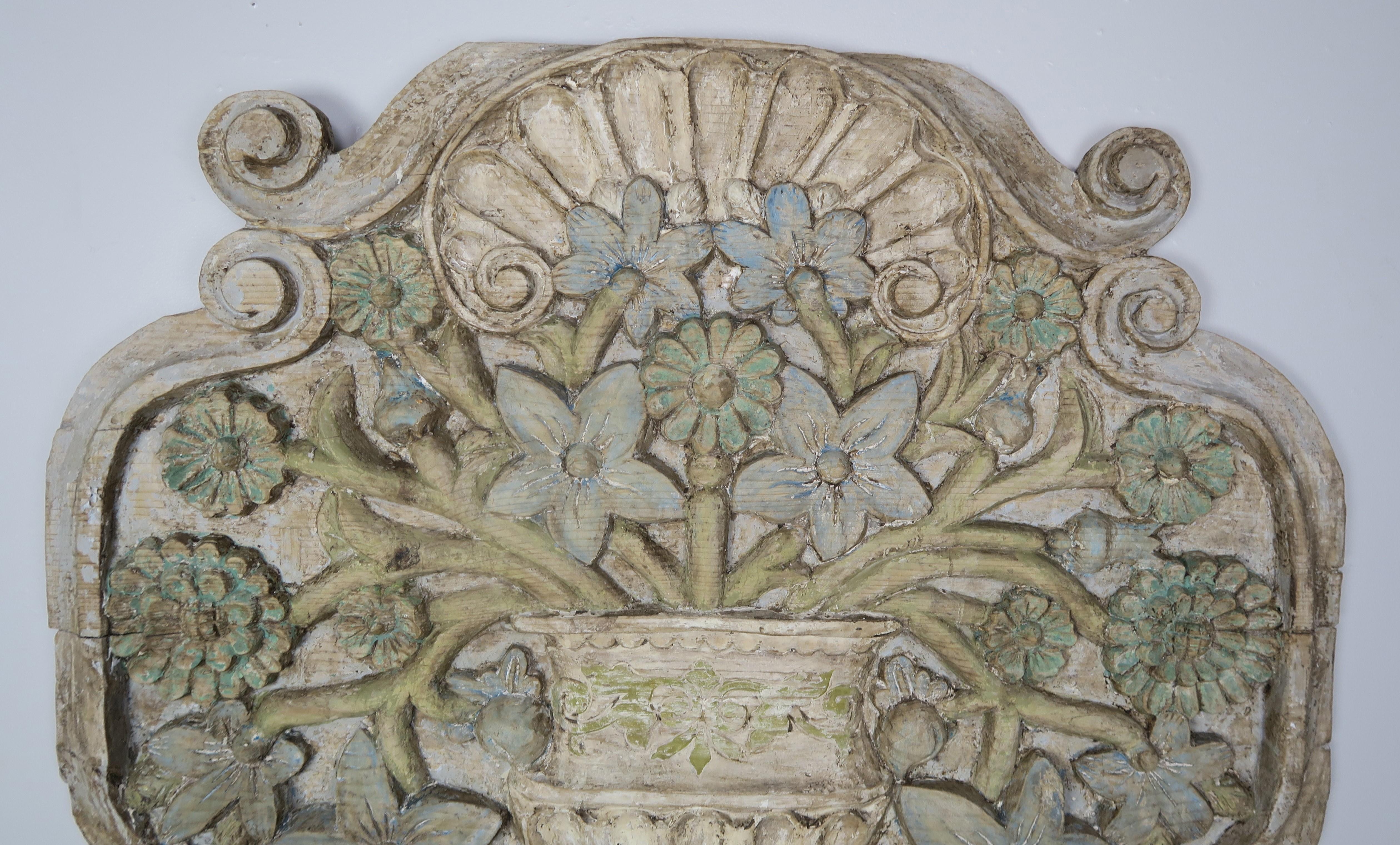 Carved wood and painted floral wall hanging depicting a beautiful carved urn adorned with flowers throughout.