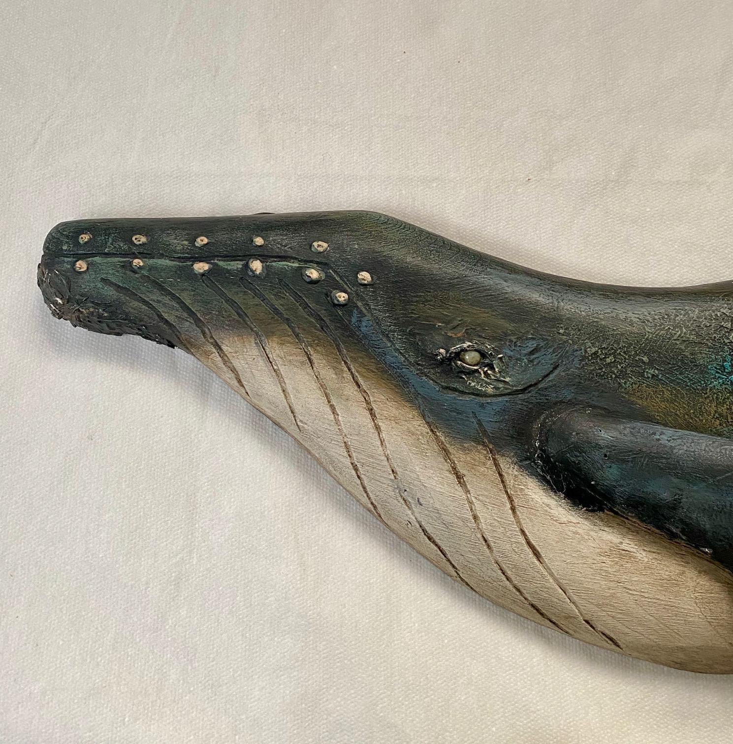 A Folk Art hand carved Humpback Whale Plaque, by the late renown Edgartown scrimshaw artist Thomas DeMont, 2010, a flat carved pine Humpback Whale with applied long pectoral fin, dramatically carved tail flukes with their wavy trailing edge, carved