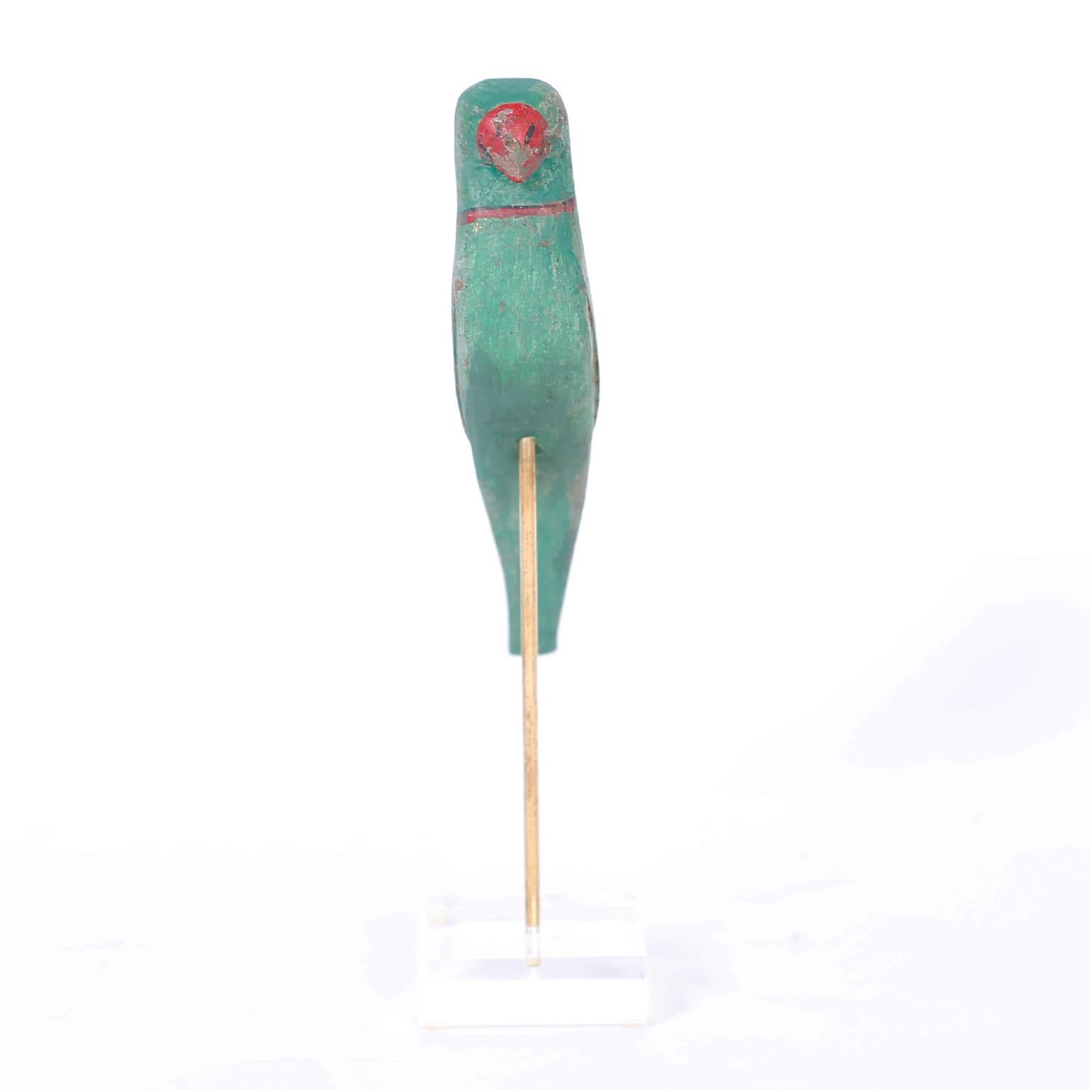 19th century Anglo-Indian bird or parrot carved from indigenous hardwood in a naive style, retaining its original paint now worn to perfection and presented on a brass and lucite stand.