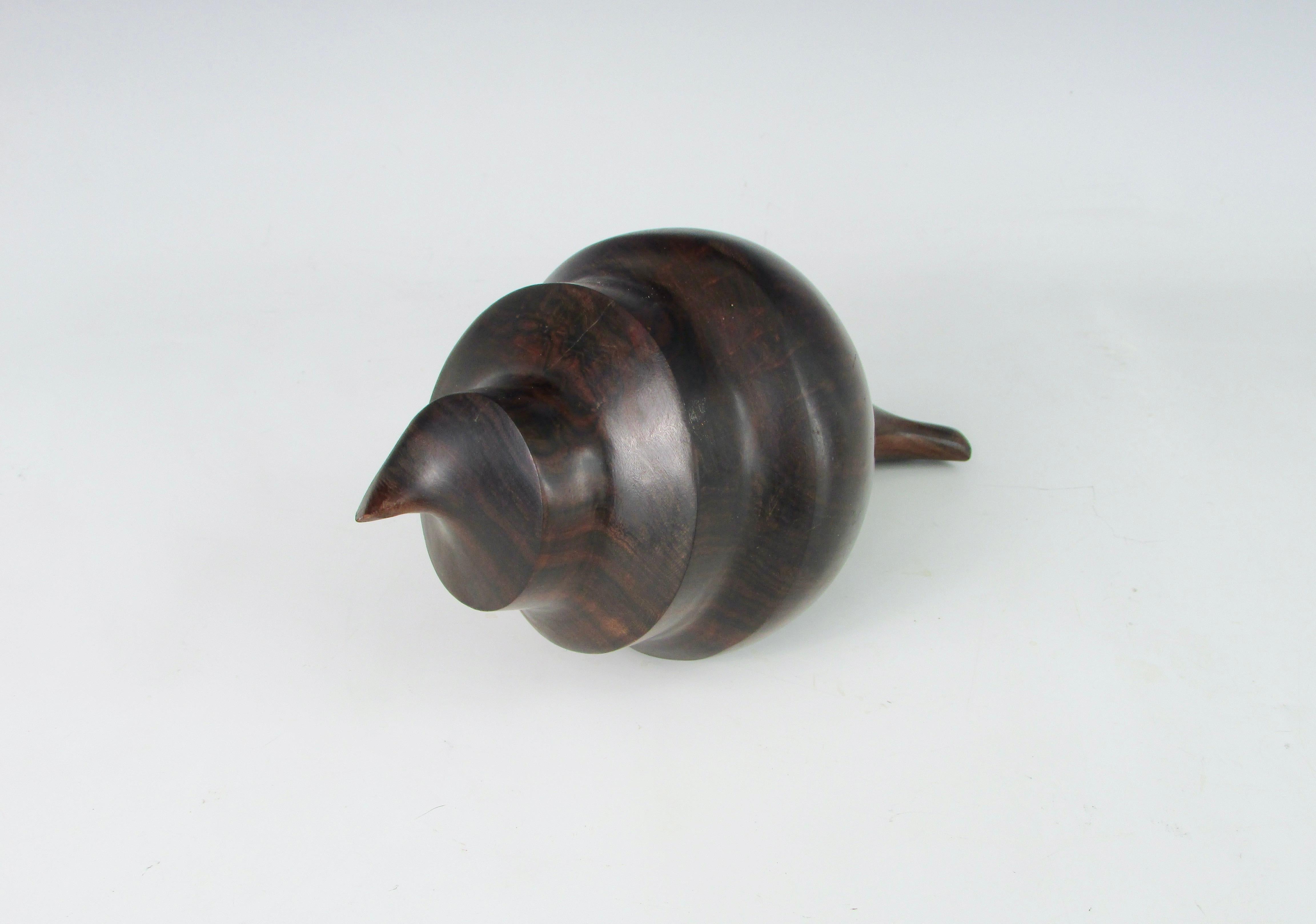 Solid piece of rosewood carved and finished smooth in the shape of a conch shell. Fine display as desk top sculpture or paperweight.