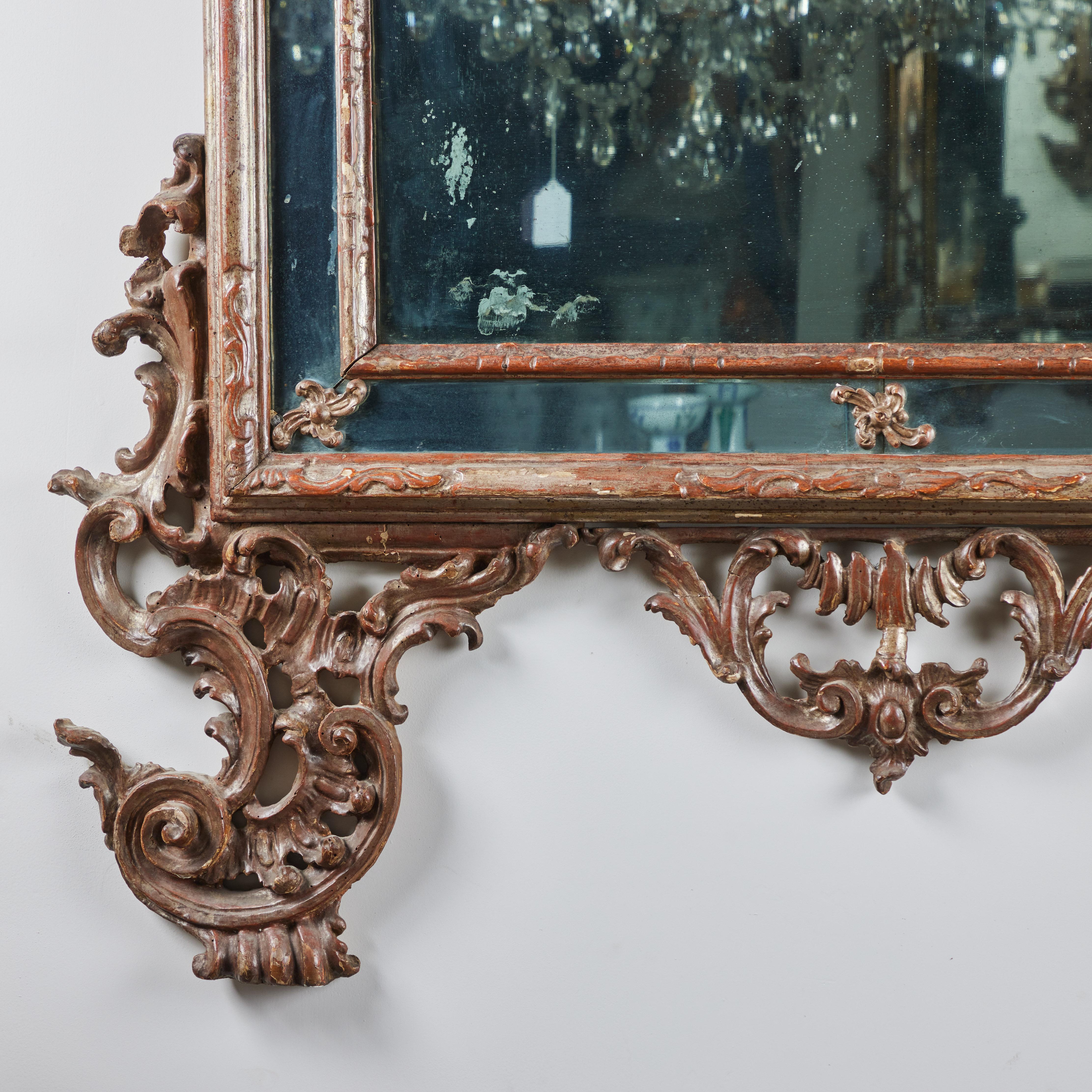Schöner Venezianer,  handgeschnitzter, gessoierter und silbervergoldeter Spiegel mit Rahmen.   Der Giebel ist nach oben hin gebogen.  Das originale Spiegelglas ist altersentsprechend marmoriert.  
