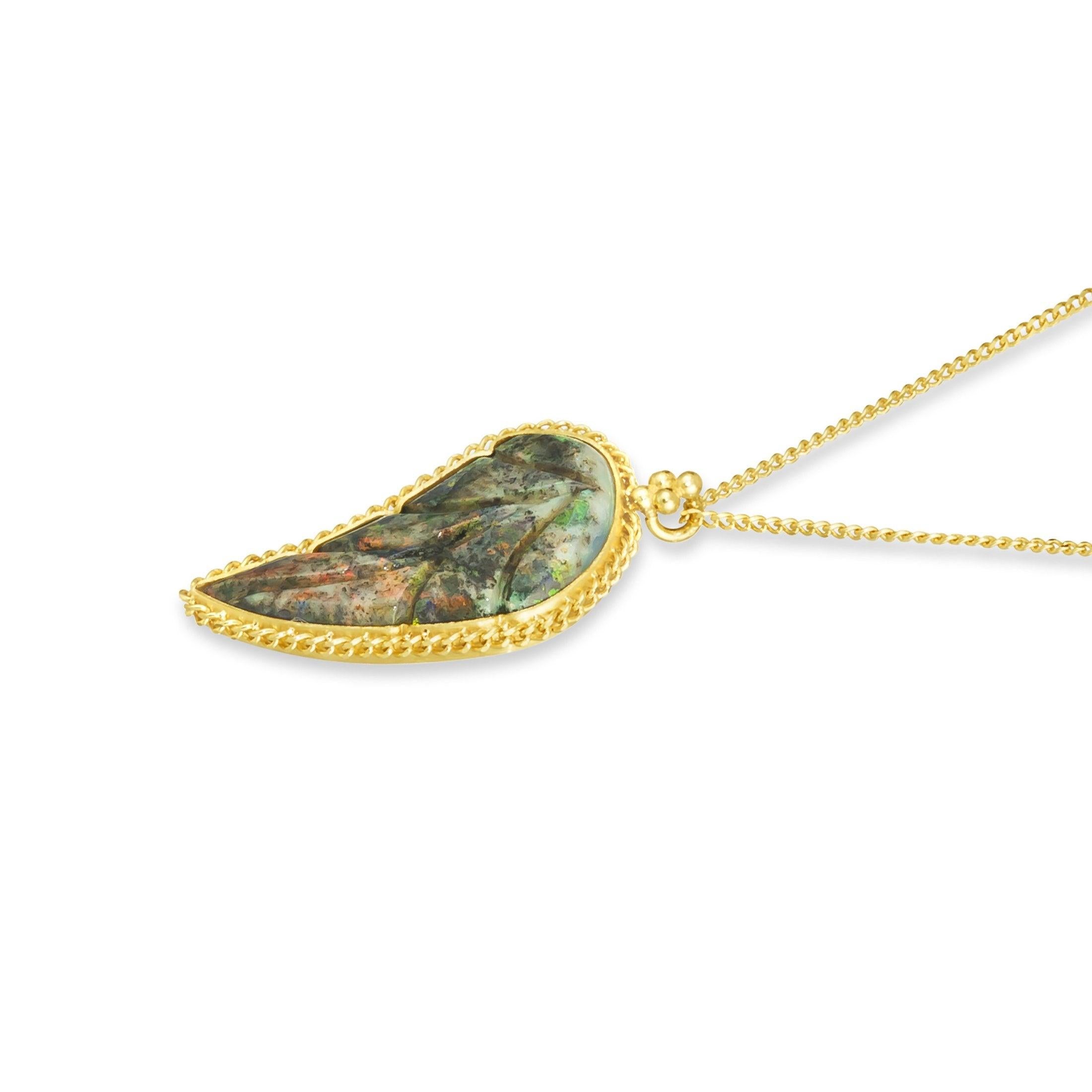 The shifting colors of this carved Andamooka Opal call to mind the lushness of sunlight dancing across an untouched forest floor. The creamy background is alive with swirling moss green hues, punctuated with flecks of darkness and bright touches of