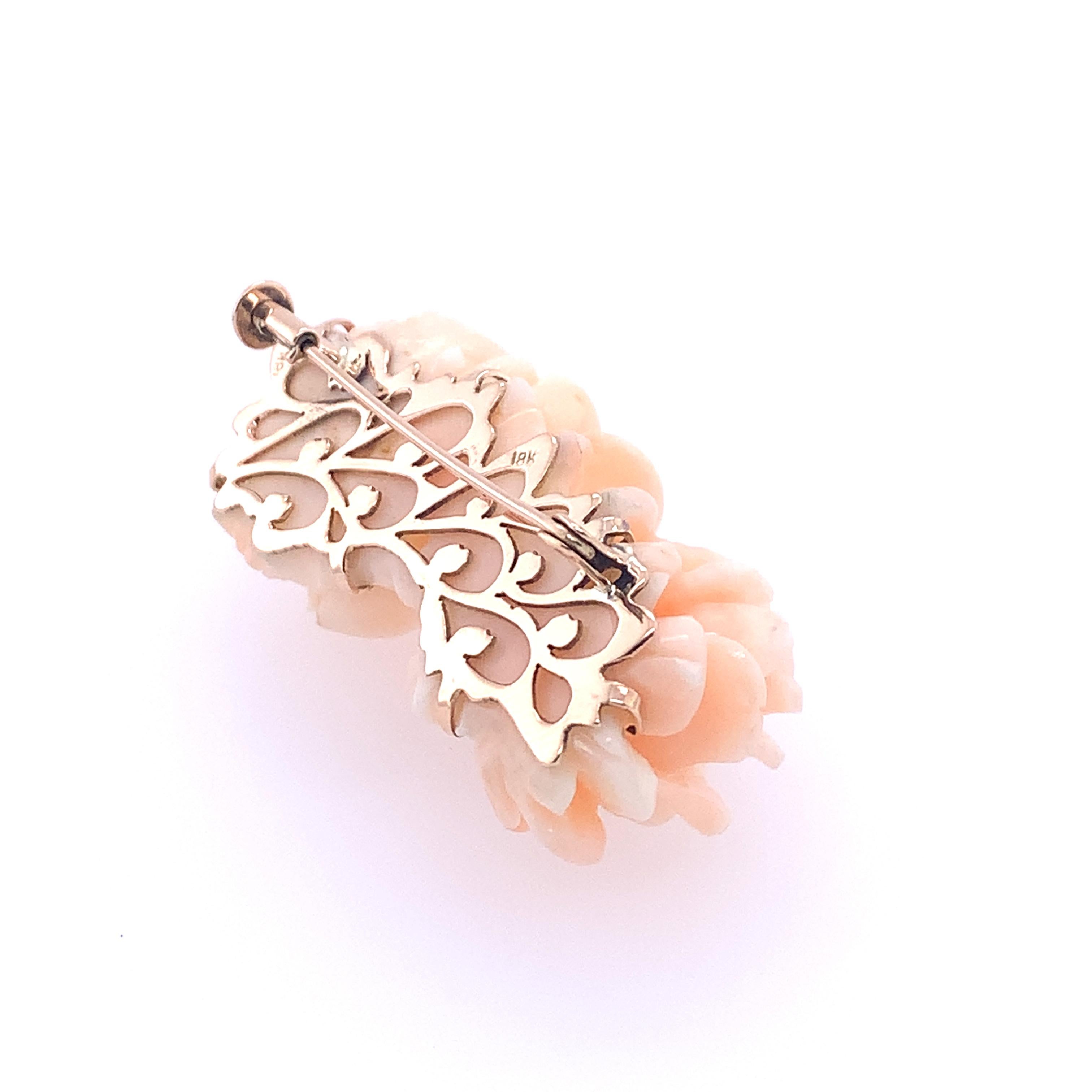 A vintage feminine angel skin coral brooch of two roses set in 18K rose gold. The hand carved roses are composed of a single piece of textured angel skin coral. on a handmade foliate designed 18kt rose gold plate. It has several shades of pale and