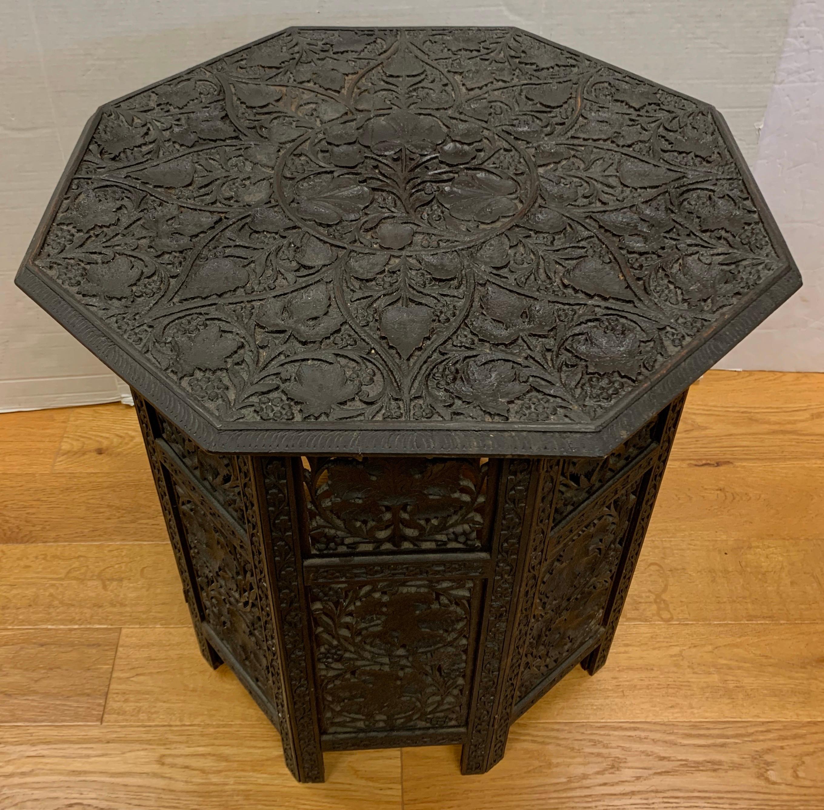 Anglo-Indian hand carved hardwood octagonal occasional table dating from the early 20th century. It has a removable top and an eight sided folding base, both intricately carved with grape vines.