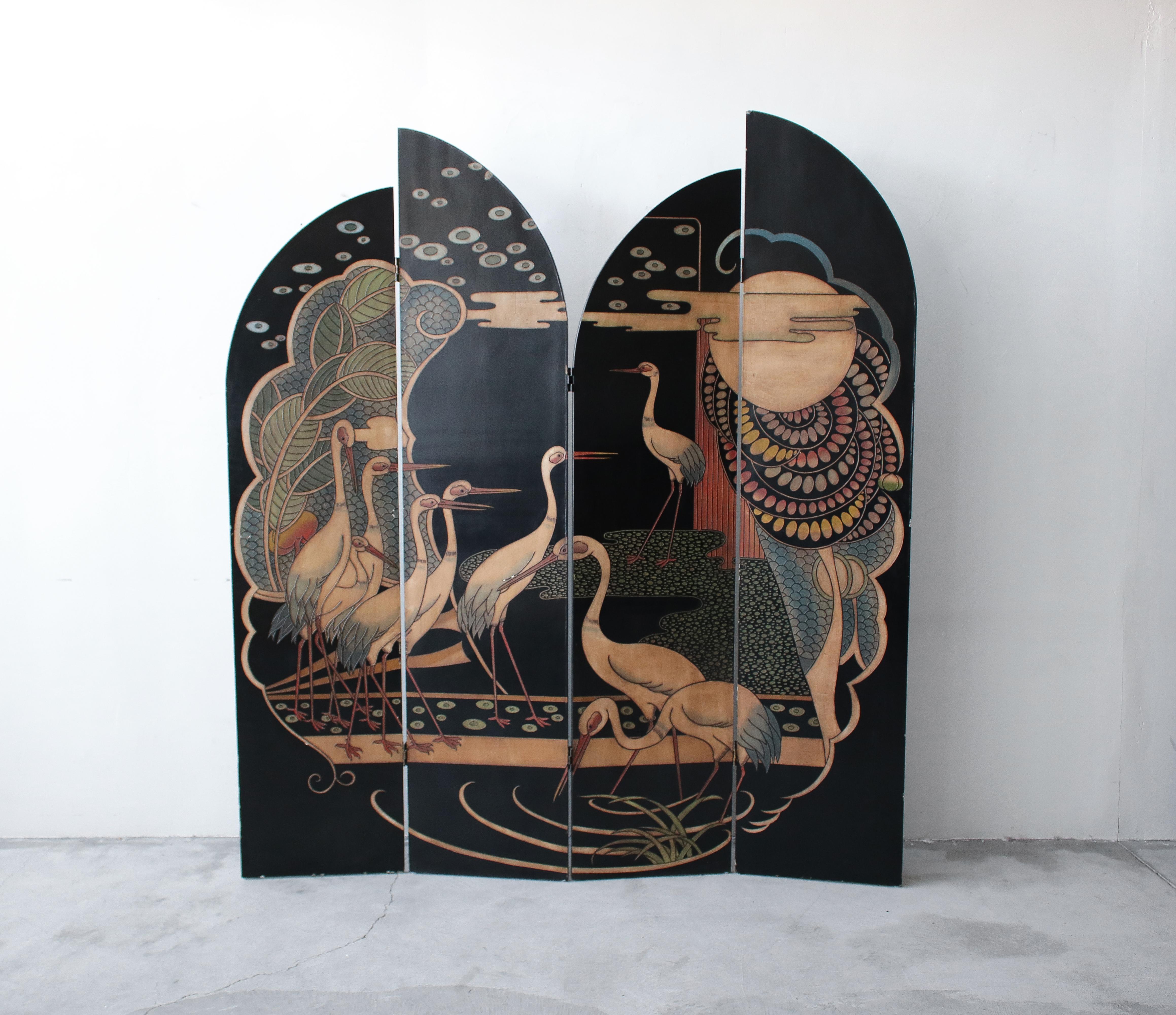 Absolutely stunning double sided, four-panel, Art Deco Asian inspired screen room divider. The divider features four tiered, hand carved and hand painted wood panels displaying a moonlit crane and foliage scene on one side and bamboo stalks with