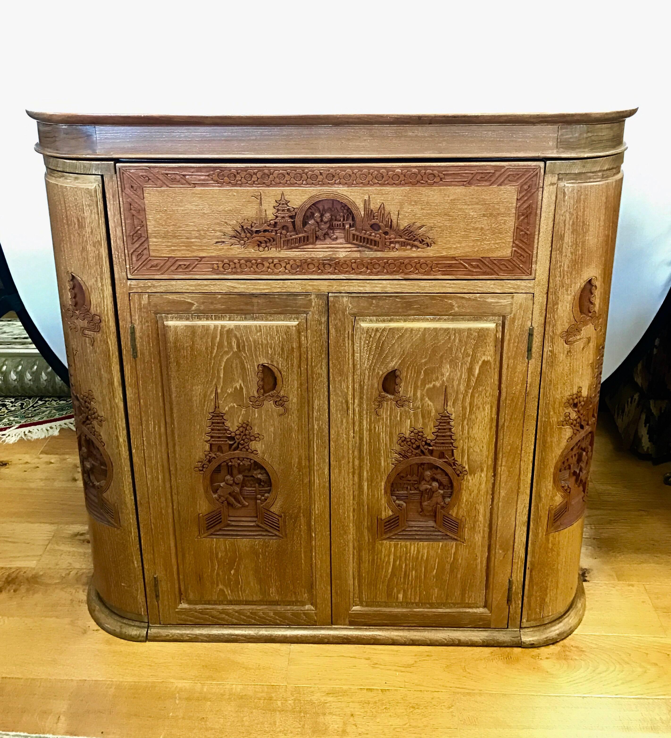 Asian camphorwood bar cabinet with amazing intricately carved detail of Chinese family life. The top portion of the bar floats up when top is opened up. It also features multiple storage options including corner doors that hold wine glasses. Front