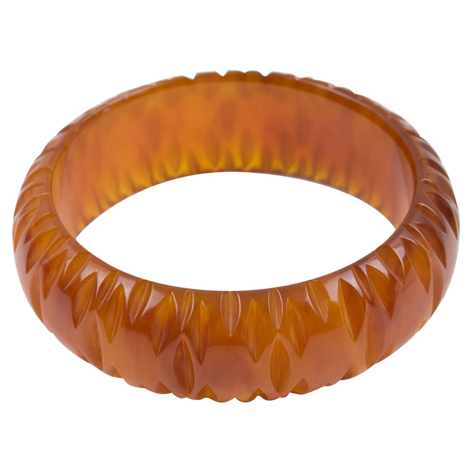 This stunning cinnamon-brown marble Bakelite bracelet bangle features a chunky domed shape with deep geometric carving all around. The piece boasts an intense spicy brown marble tone with red undertones, cloudy swirls, and lots of transparency in