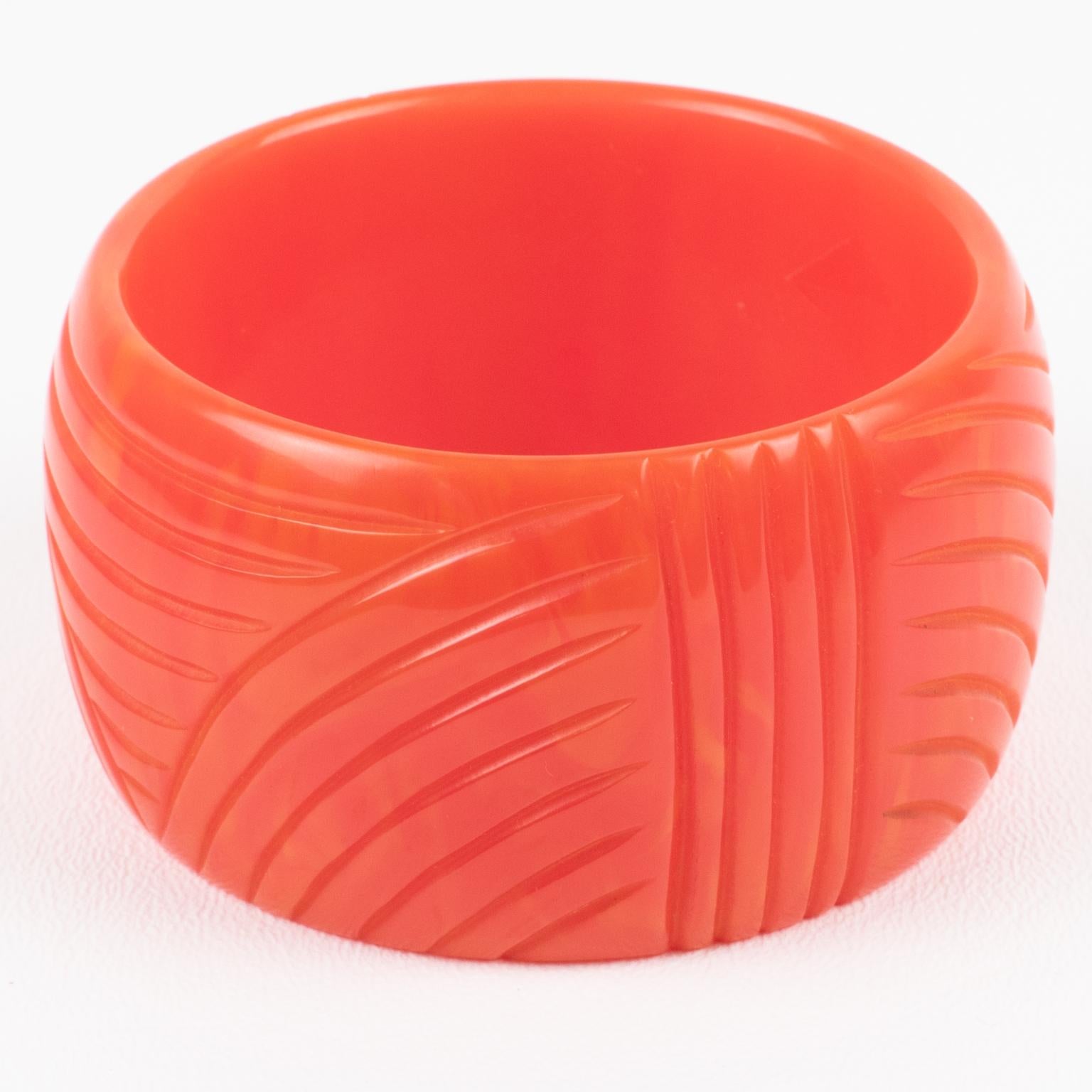 This is a lovely pink tequila sunrise marble Bakelite bracelet bangle. It features a rare chunky domed oversized shape with deep geometric carving all around. The color is an intense pink marble tone with orange cloudy swirling also called tequila