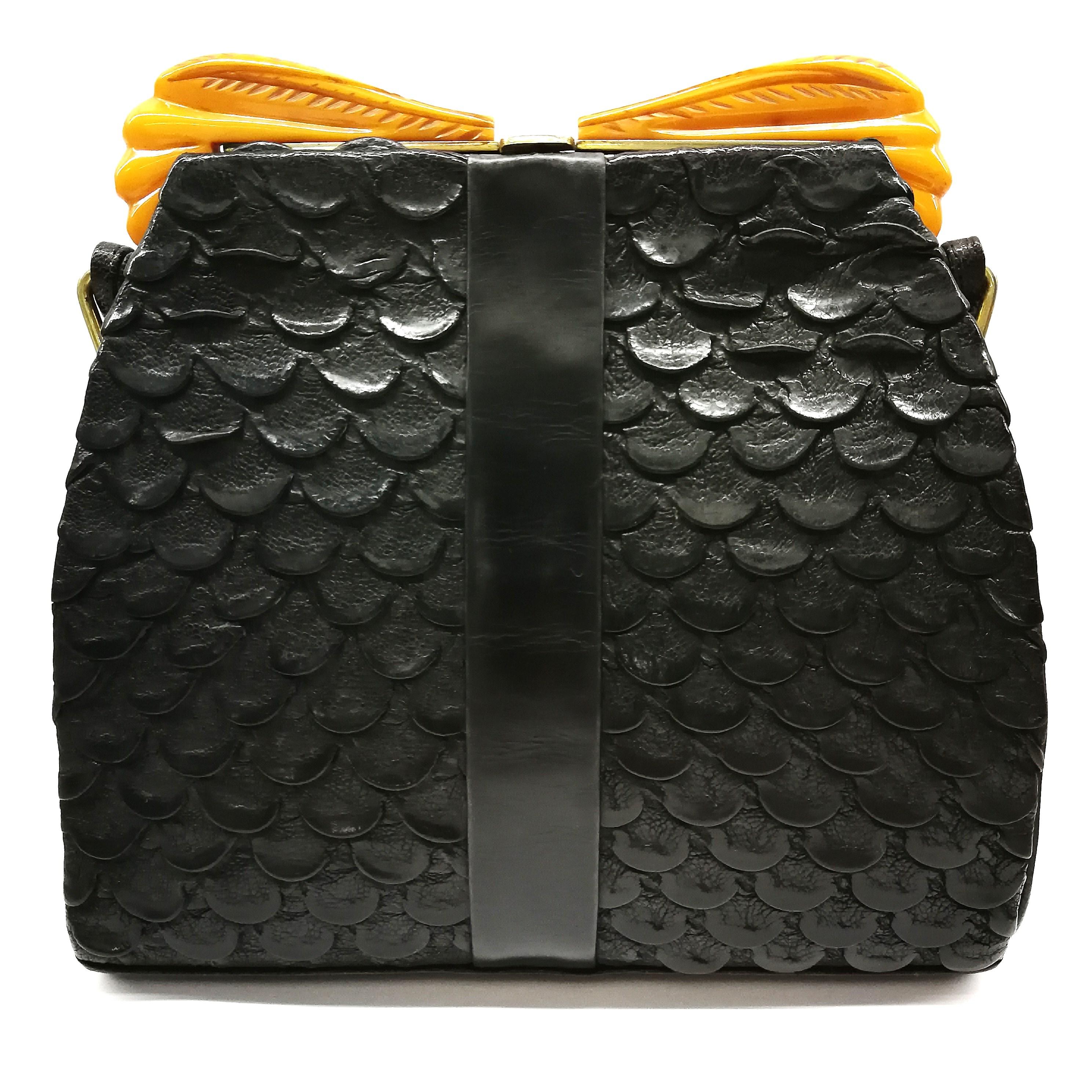 A rare and very individual thing, this 1930s handbag is composed of a very unusual leather, most decorative. Crowned with beautifully carved opaque amber Bakelite 'wings', the combination of the black and highly textured leather and the carved