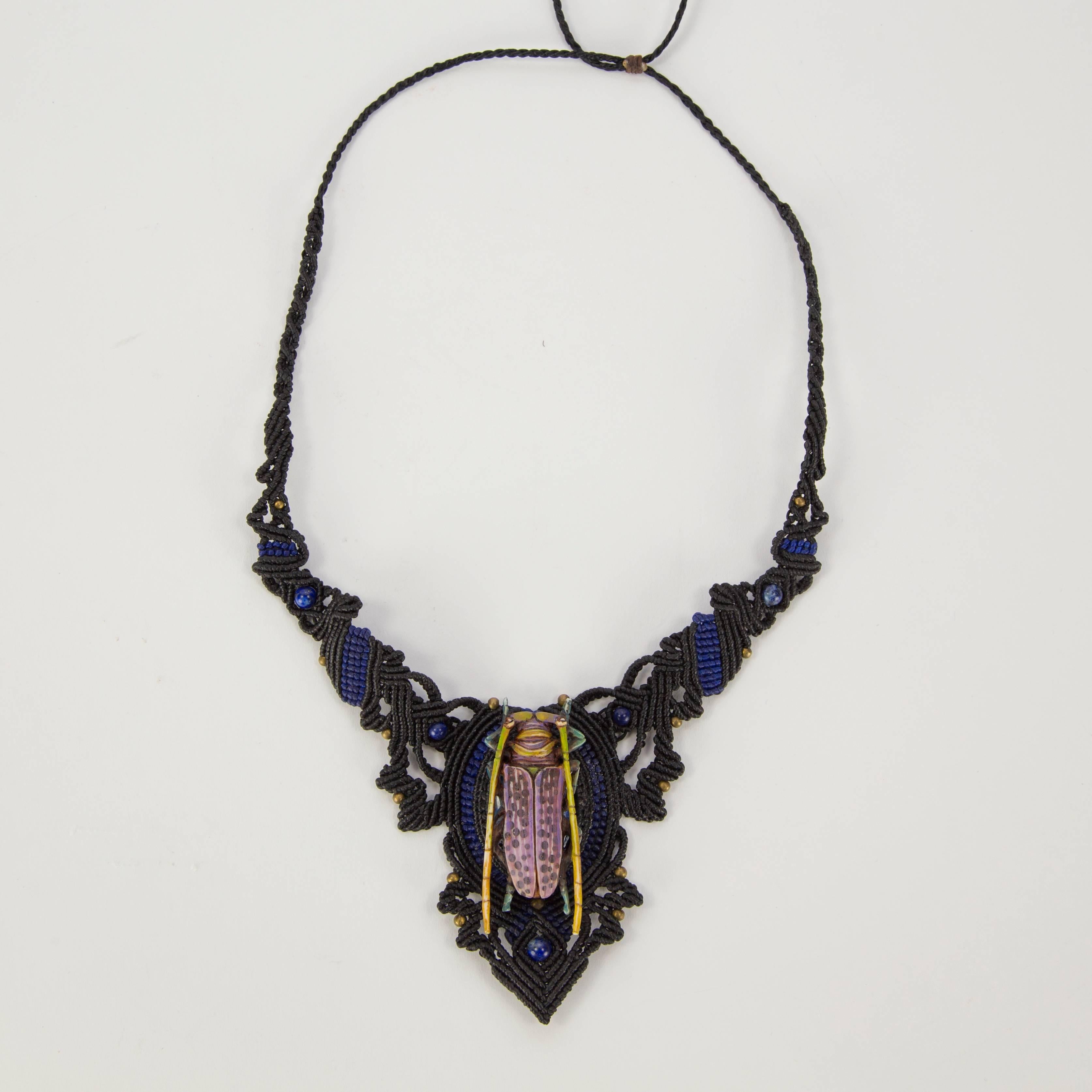 This beautiful necklace is hand carved bone and hand colored by a master Balinese painter. This delicate Beetle dazzles the imagination. Set on an intricate hand knotted neck-piece with Lapis Lazuli and brass beads.  Adjustable length 12” -30”;