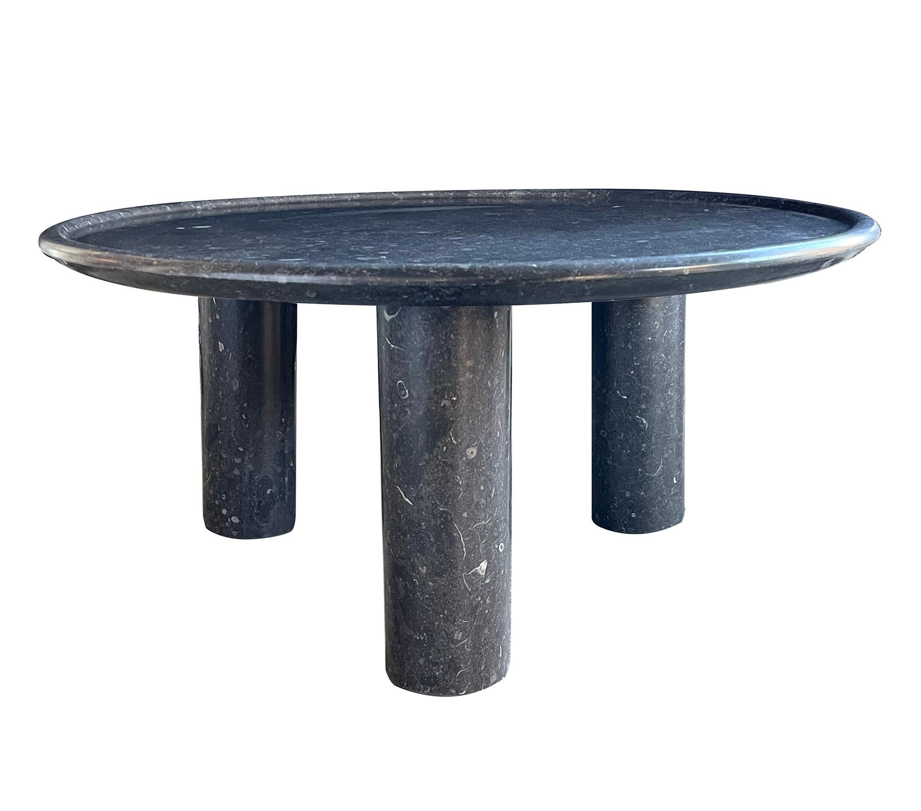manufactured from Belgian bluestone with a honed finish and embedded with fossils, the table is comprised of a round dish top top all raised on three cylindrical supports. New with only minimal wear expected; table is ideal for exterior design