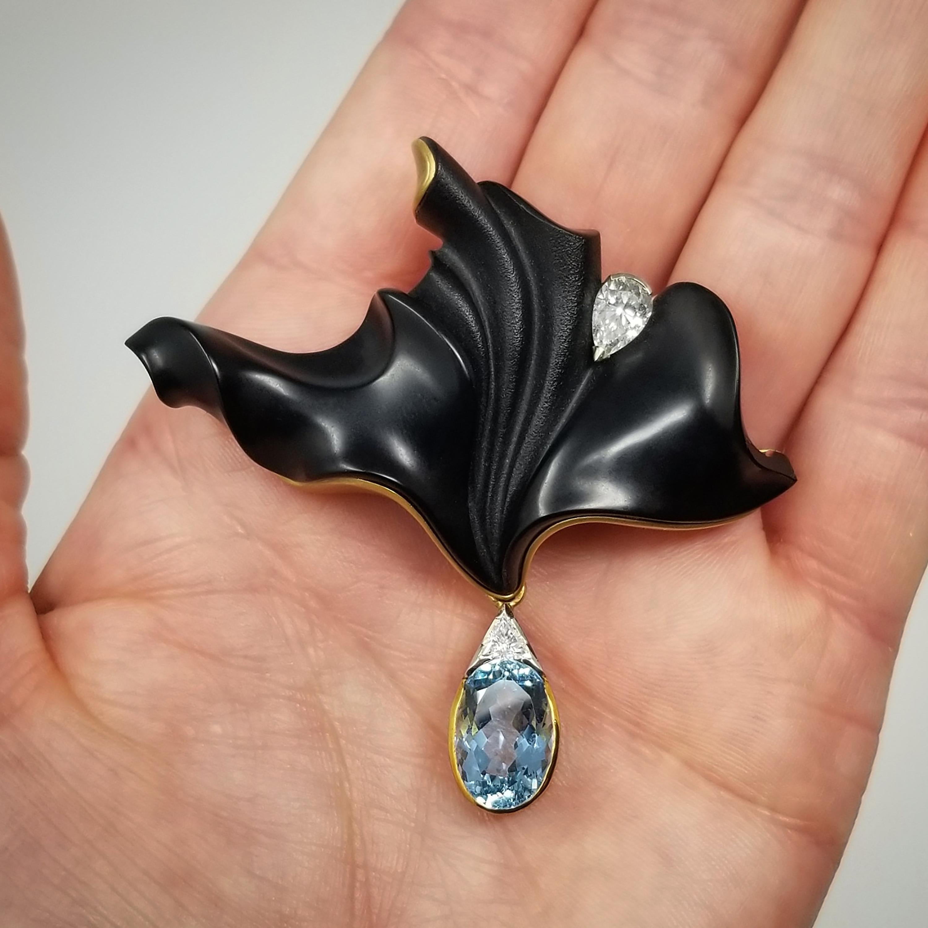 La calcedonia negra natural tallada por Steve Walters llamará la atención se lleve como se lleve en esta lujosa pieza de joyería. La gema tallada se abre con elegancia y una gota de aguamarina y diamantes se balancea libremente. Un diamante en forma