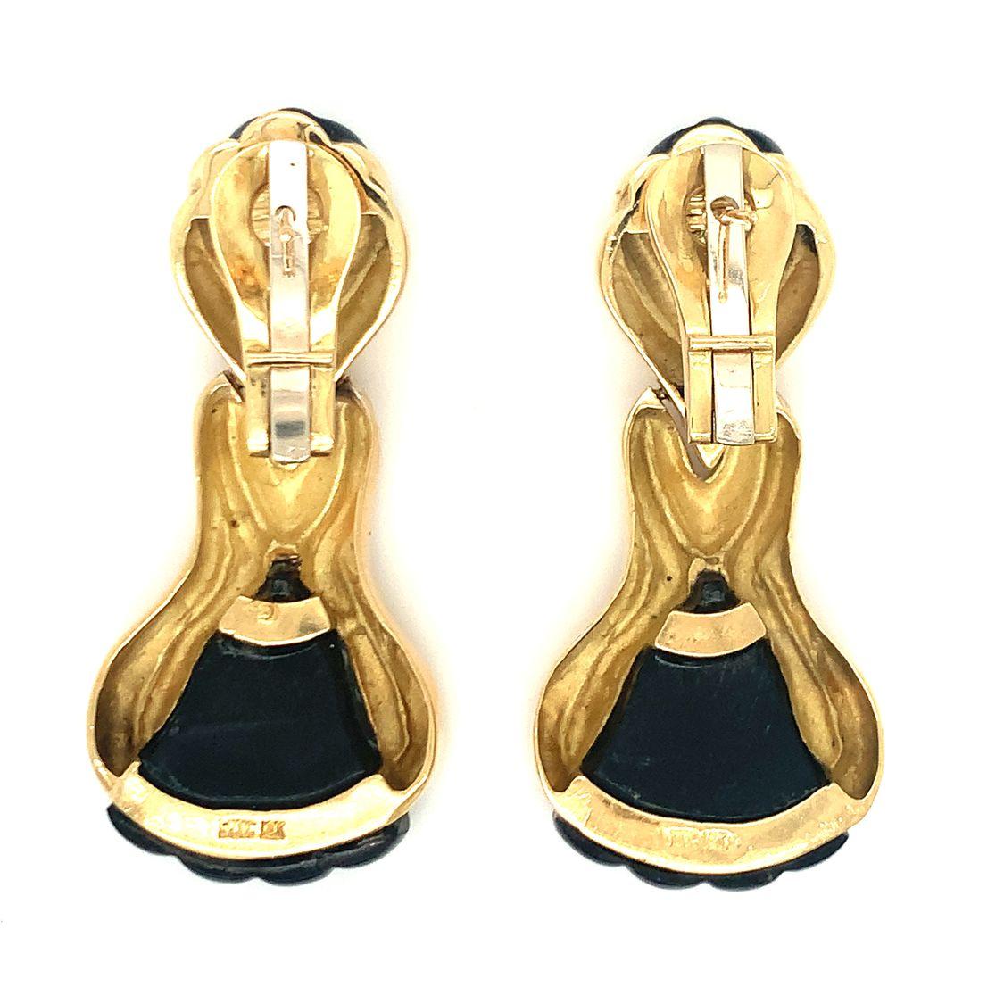 This stunning pair of 18K yellow gold earrings by Wander features a distinctive design that showcases fluted gold detailing and intricately carved black onyx portions at both the top and bottom. Measuring 2 inches long by 1 inch wide, these earrings