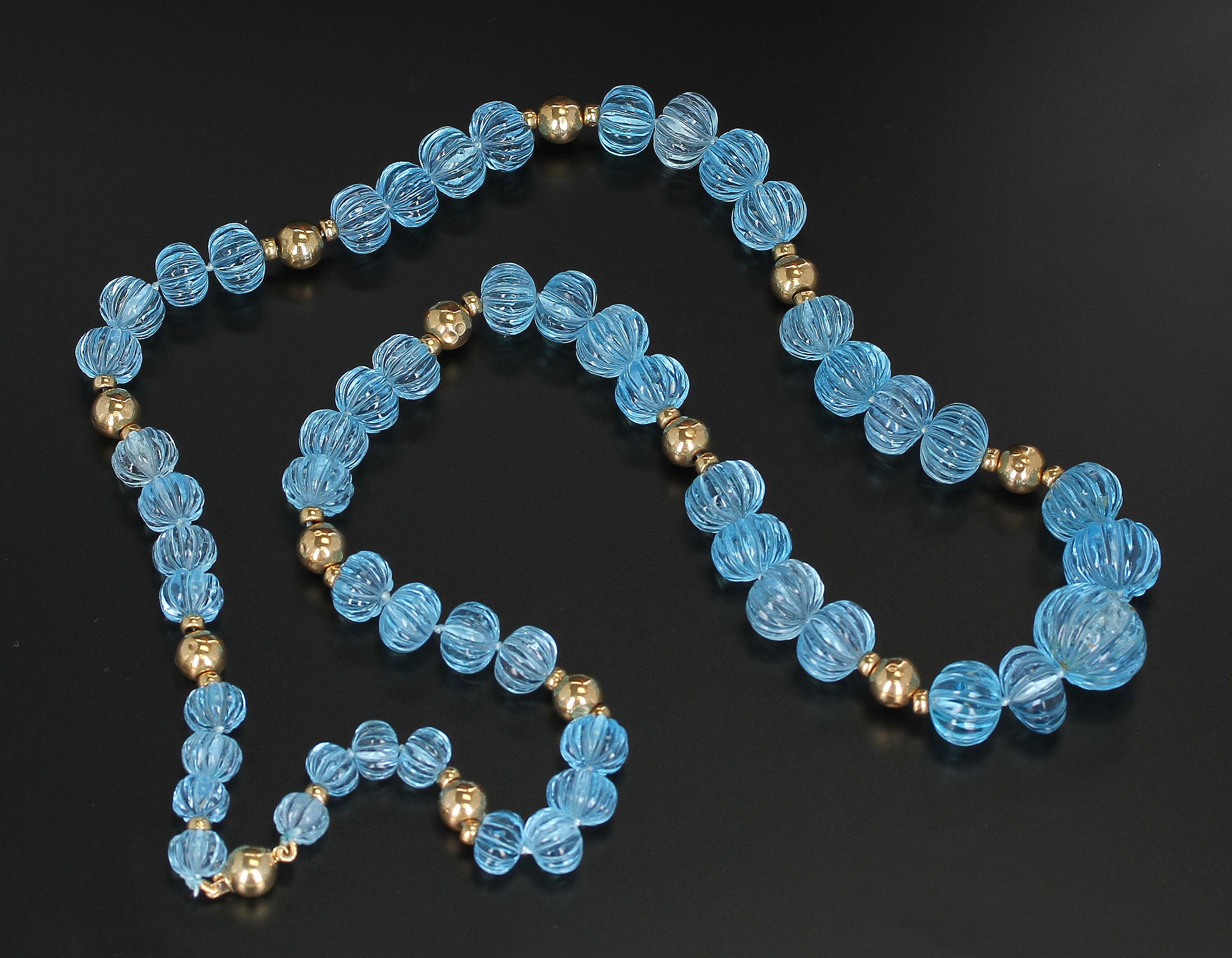 A stunning necklace consisting of Carved Blue Topaz ranging from 8MM to 18MM with 14K Gold Beads. GW: 595 cts. Length: 26.5