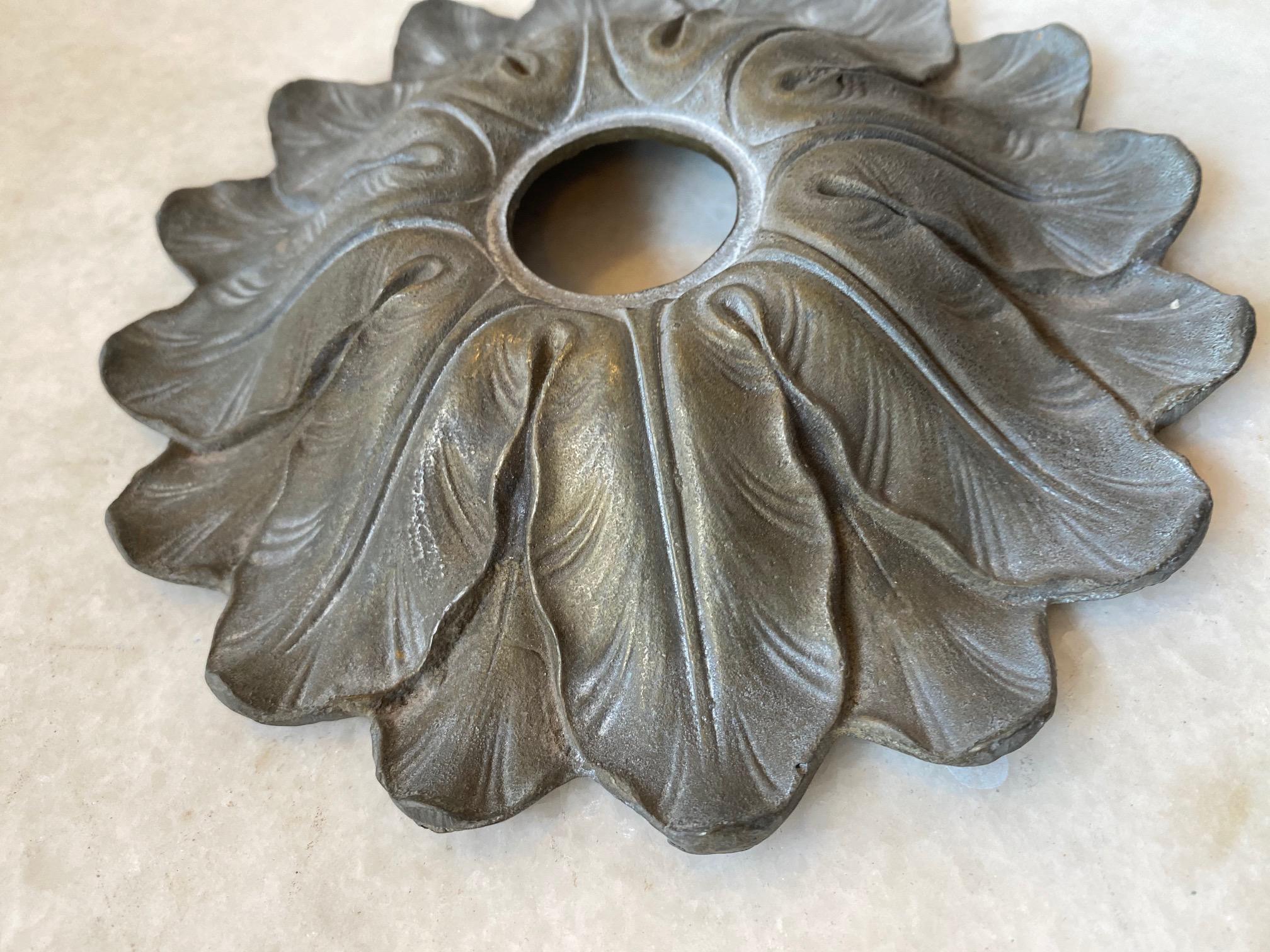 This escutcheon is made of brass and depicts a leaf like design. 

Measurements: 6.5” W x 1” D.