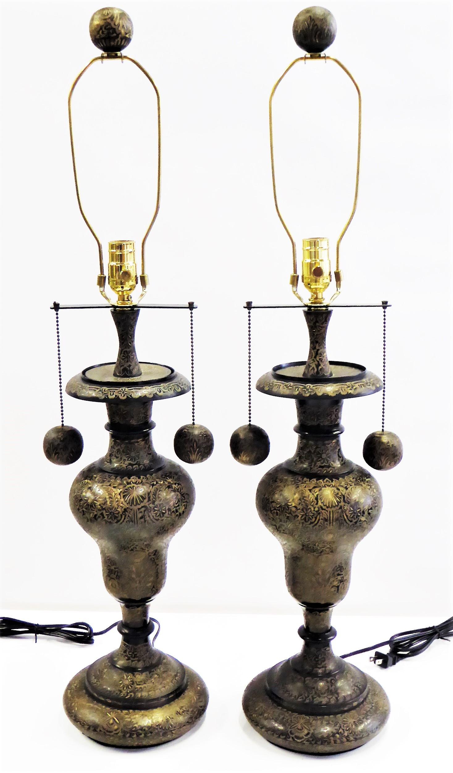 REDUCED FROM $1,280....Exquisite arabesque floral carved brass shines brightly through the patination on this pair of brass vase form lamps with matching carved hanging balls and finial. Antique forms, elegant and rich. Rewired and with new UL three