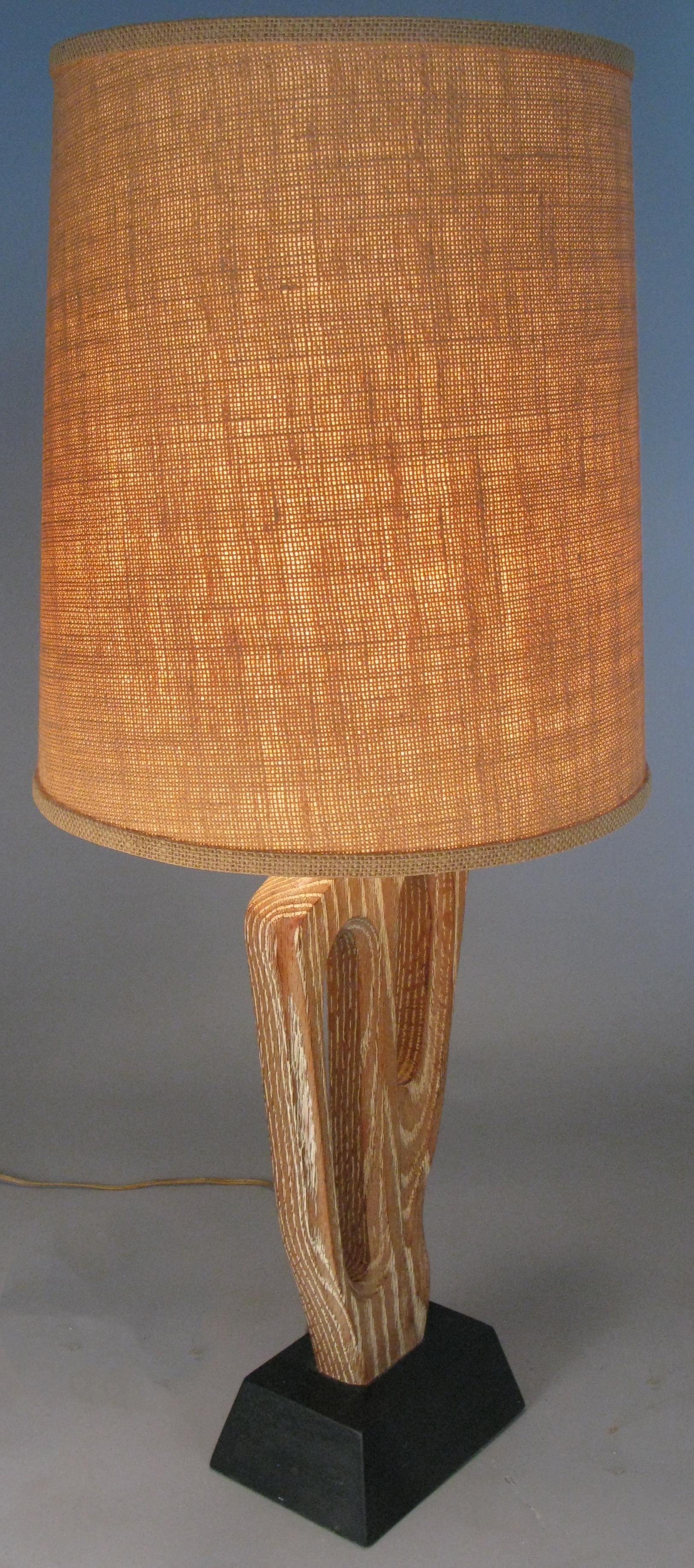 A beautiful vintage 1950s table lamp with an abstract carved and cerused oak form mounted on its original lacquered base, signed by the artist Yasha Heifetz. with its original shade.