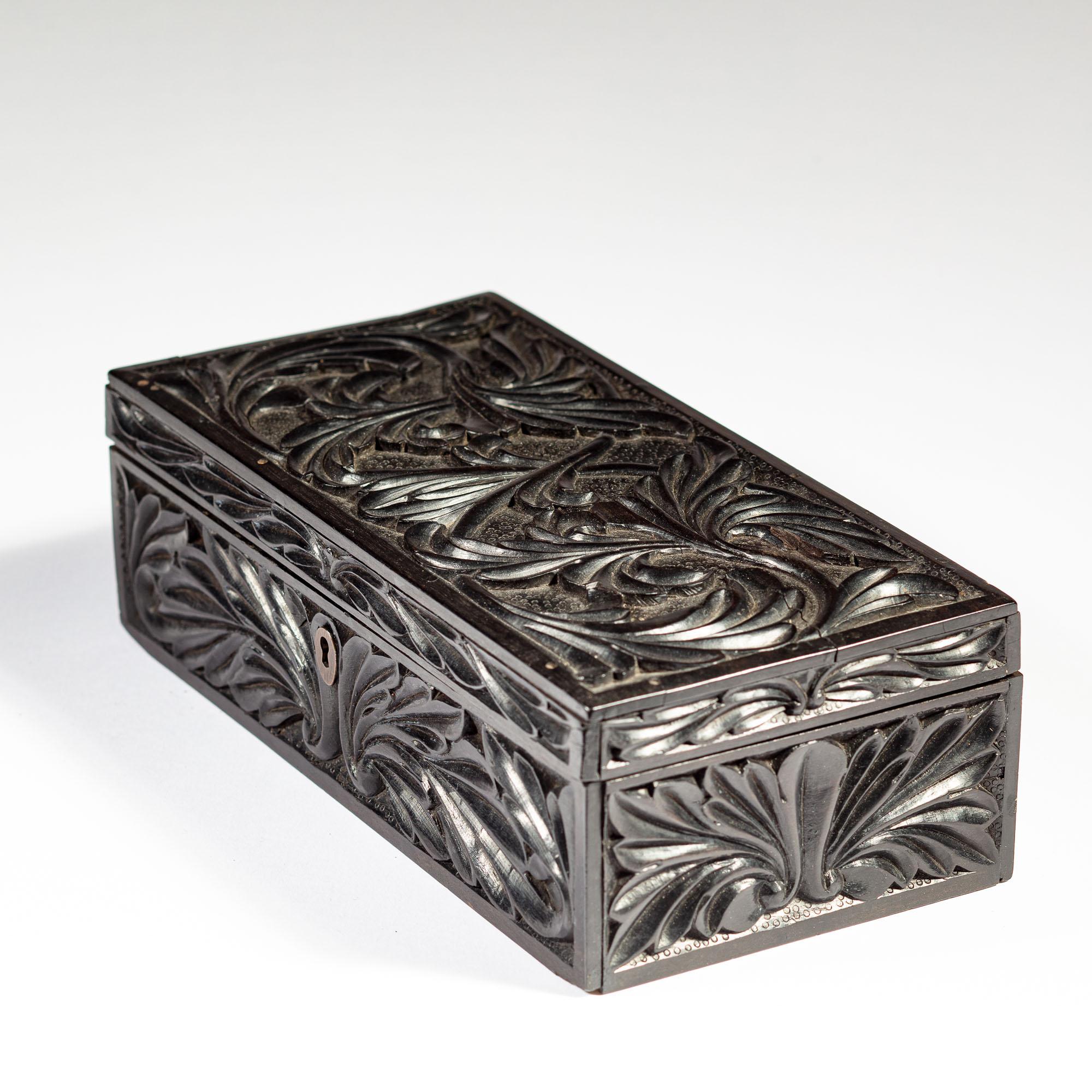 A charming mid 19th century carved ebony box with intertwined foliate ornament on all sides on a punched ground, opening to a void interior, the sides and lid with inlaid bone dots and an elephant wearing a red cloth above the name GALLE – A town in