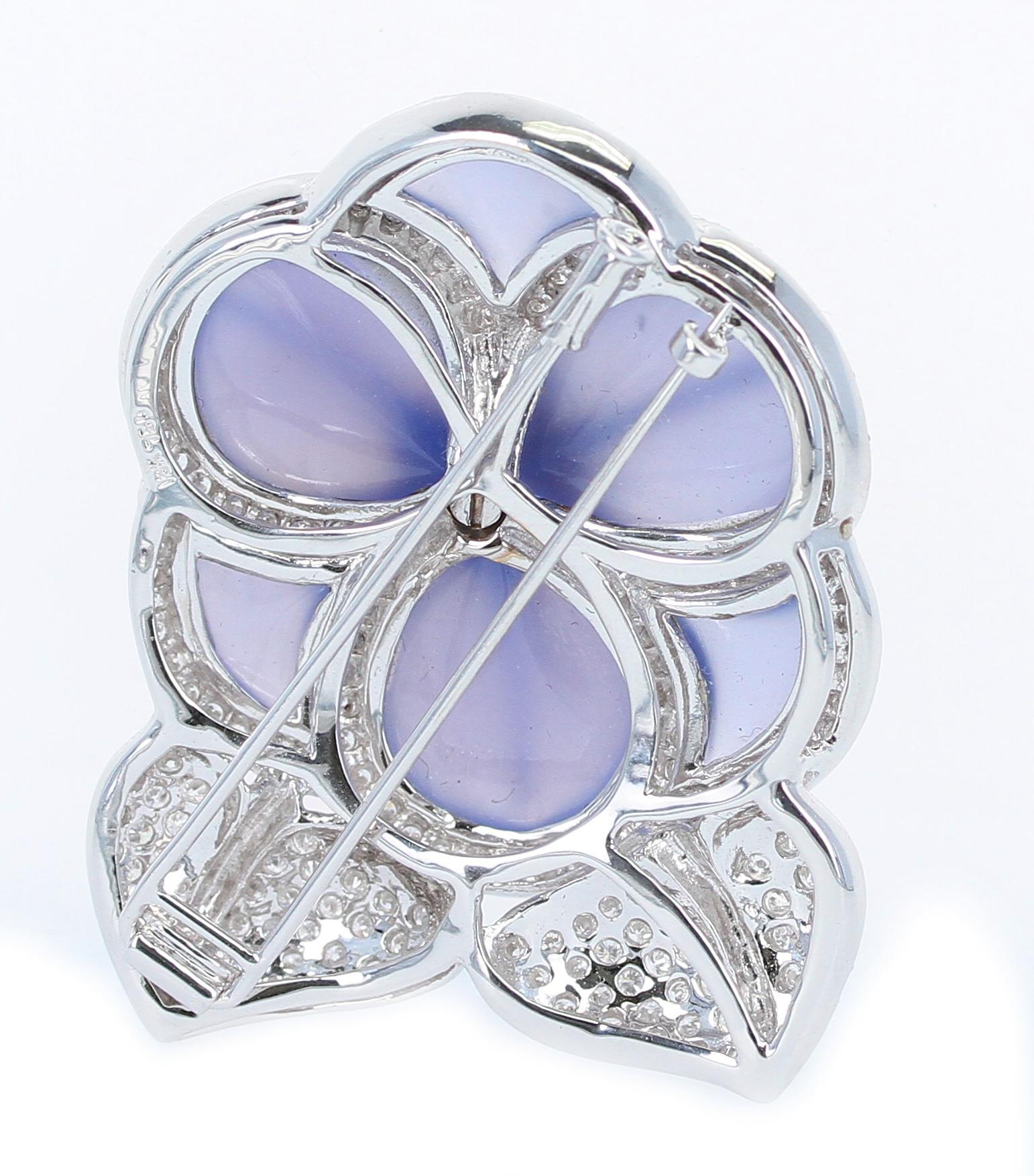 A stunning carved chalcedony brooch accented with sapphire cabochons and diamonds. The chalcedony acts as petals and the sapphire cabochons are the pistil of the flower. The round diamonds are the leaves of the flowers. 18K White Gold. 2 x 1 1/2
