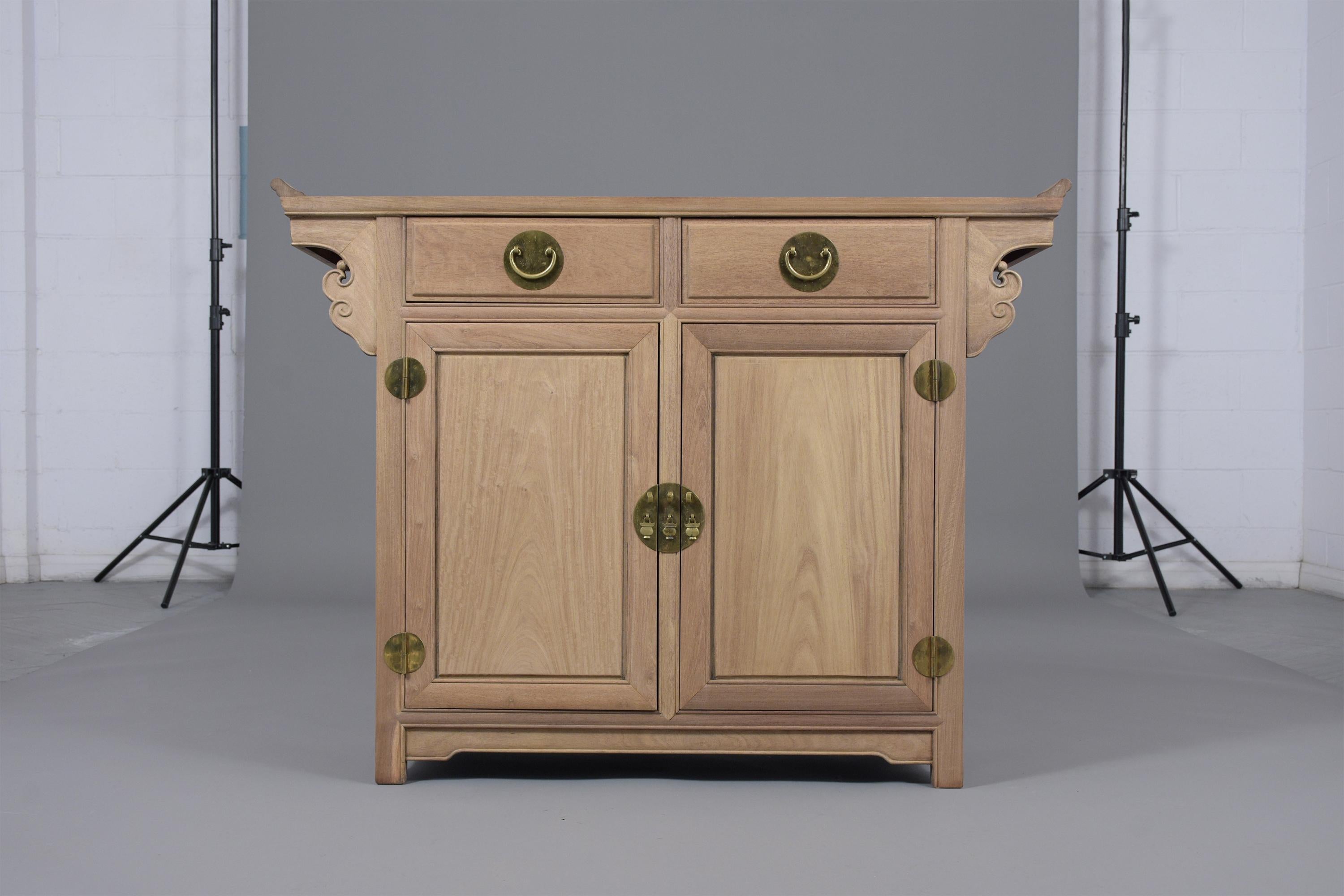 This vintage Chinese cabinet hand-crafted out of mahogany wood has been fully restored, features a unique bleached wood finish and carved arched motifs on the top. The cabinet has two top drawers and two doors with single brass ornament details and