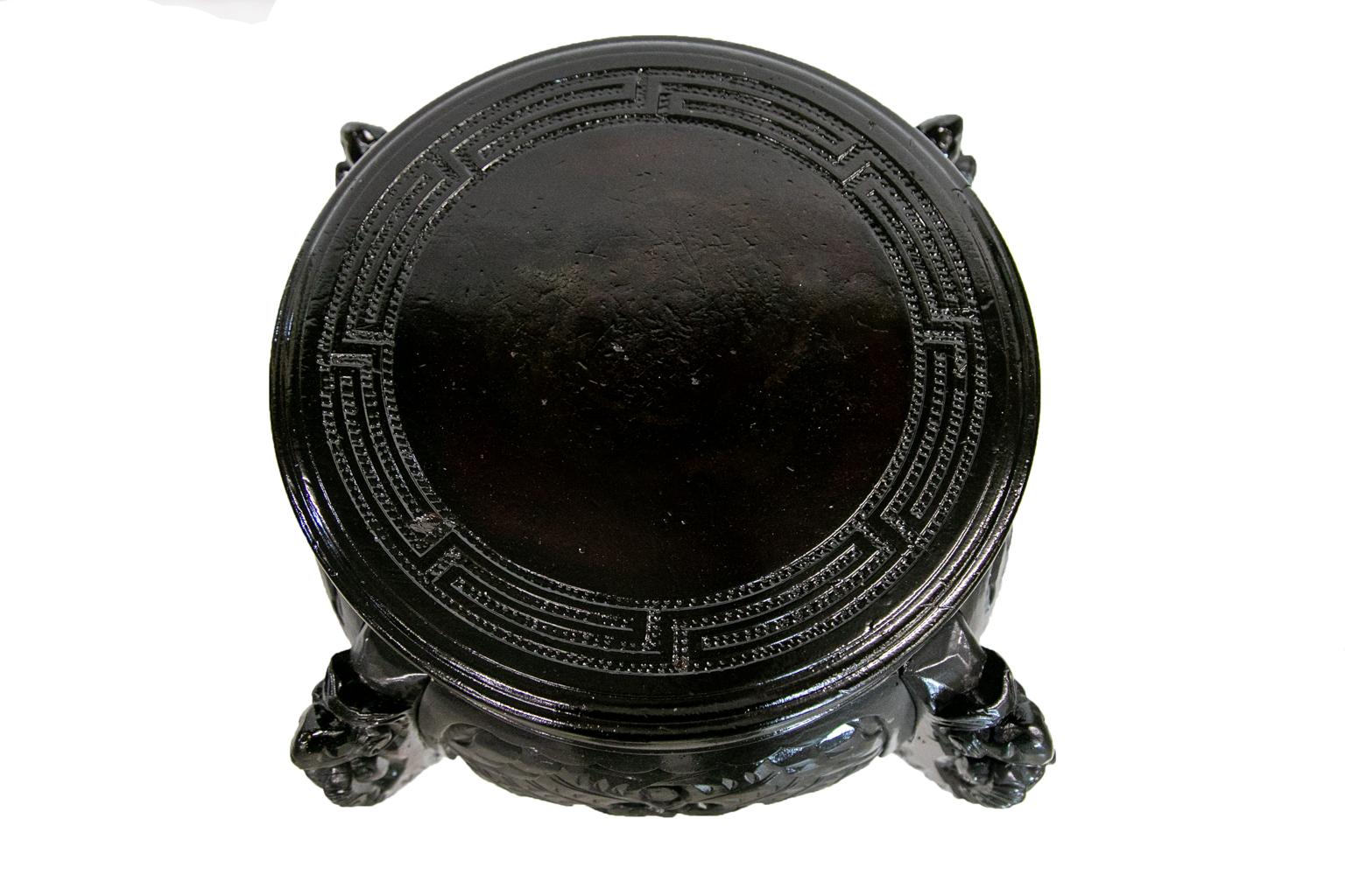 This carved Chinese black lacquer stand has a geometric carved top. The aprons have carved wings. The legs have stylized animal heads and leaf carvings extending down the legs to the feet.
   