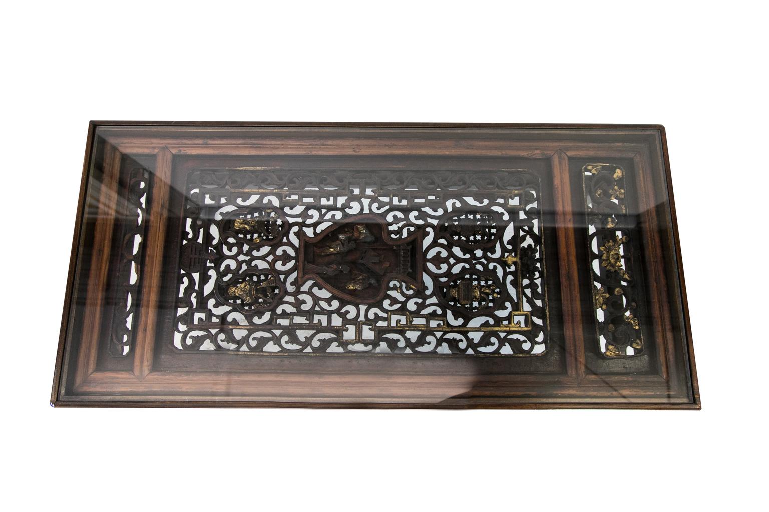Carved Chinese coffee table is made from a carved Chinese panel with a custom made base. The panel is carved in high relief with gilt highlights. The scene depicts various vases and people figures.