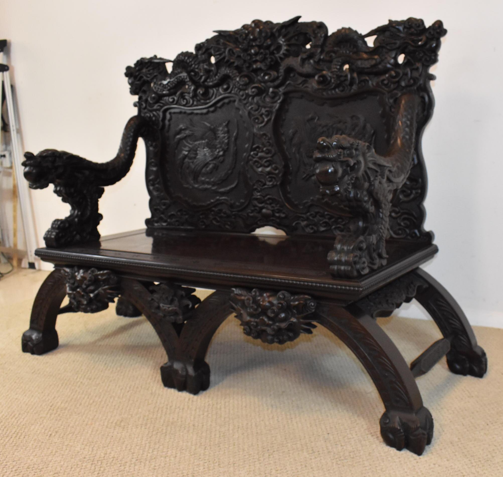 Very heavily carved dark wood Chinese dragon head bench. Chinese pheasants carved into the back. Very good condition. Light wear. Dimensions: 24