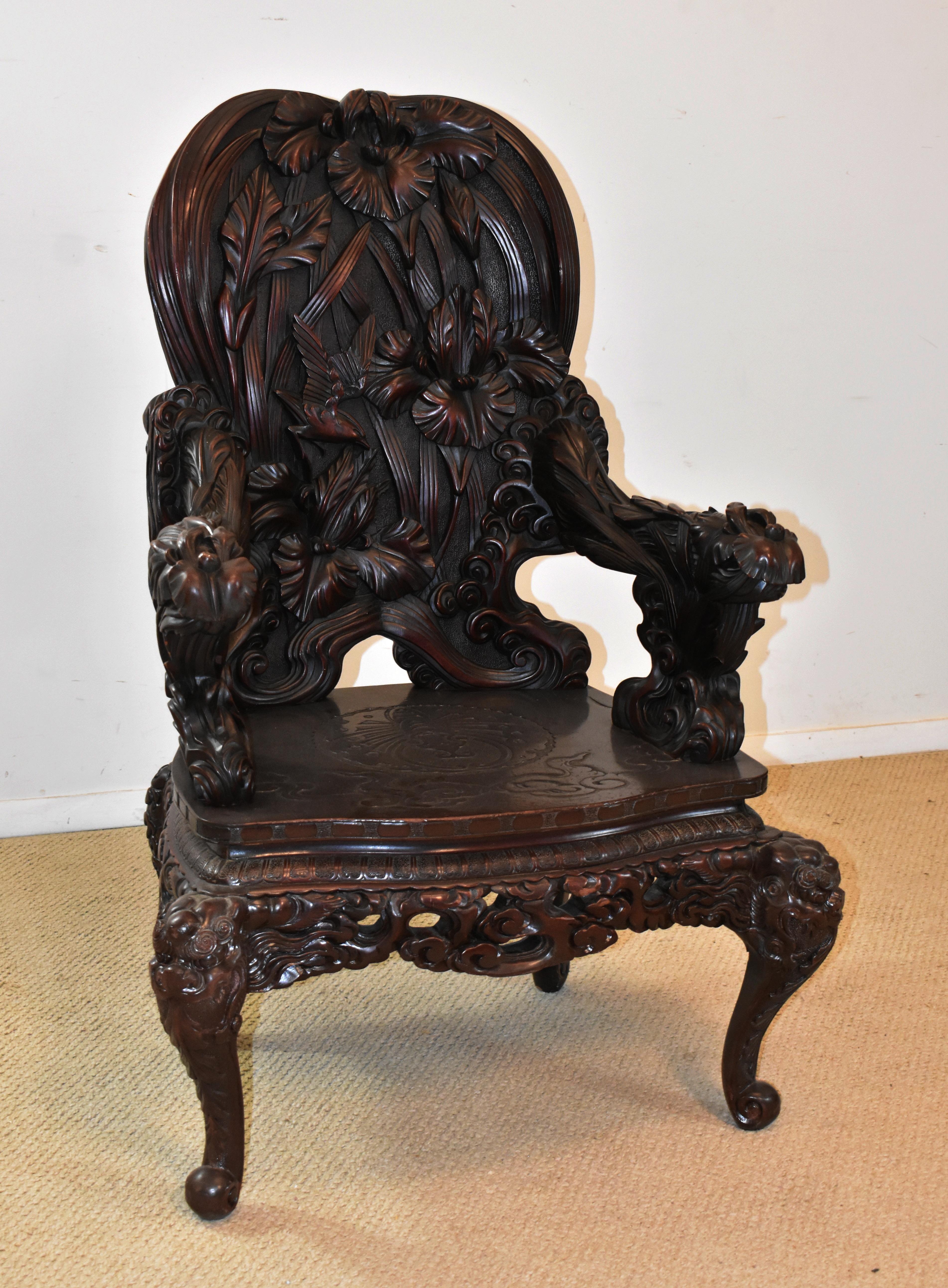 Carved Chinese high back fantasy chair. Details of a bird, iris and dragon head on the legs.