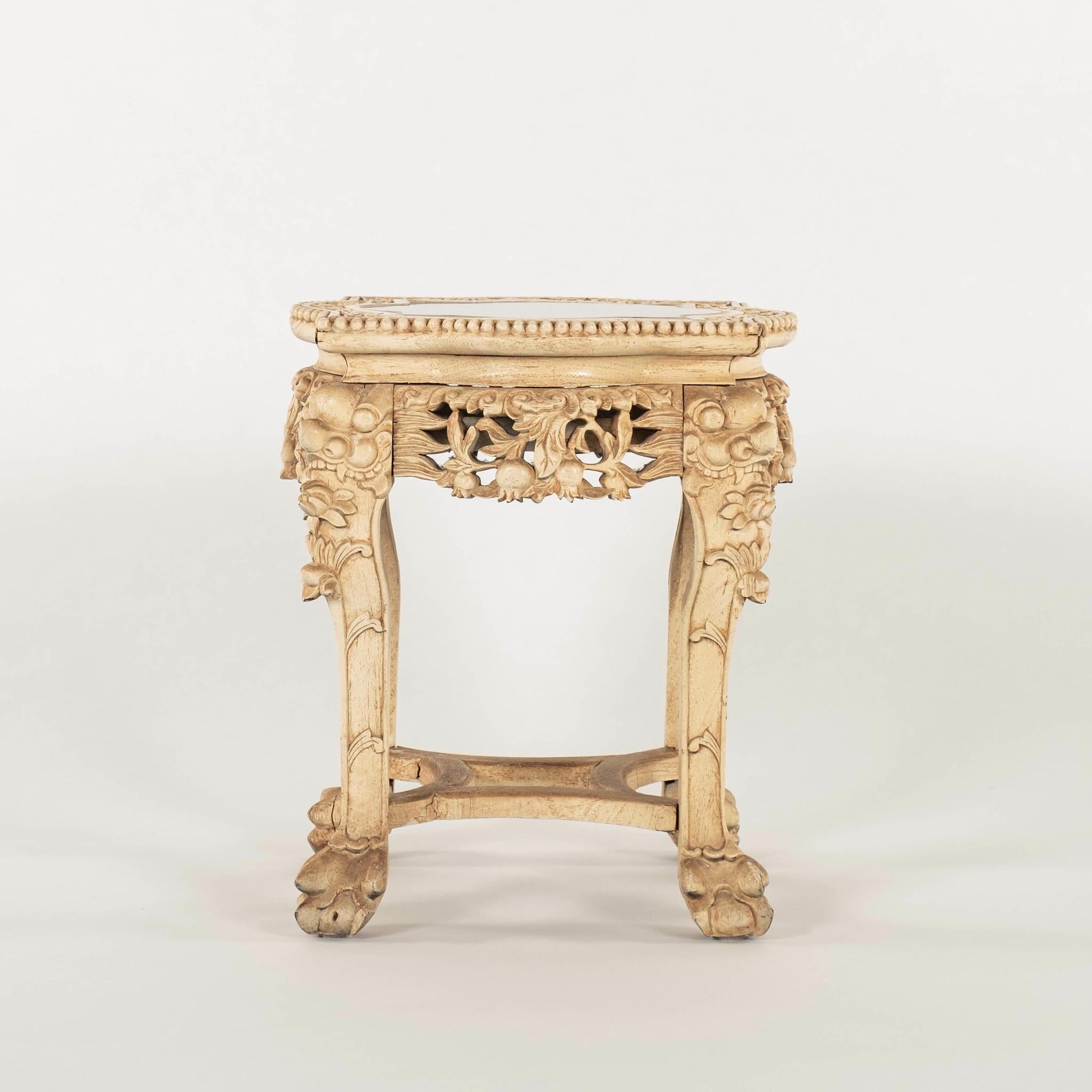 A Chinese carved occasional table with mirror top featuring dragon heads, floral and foliage motifs. 