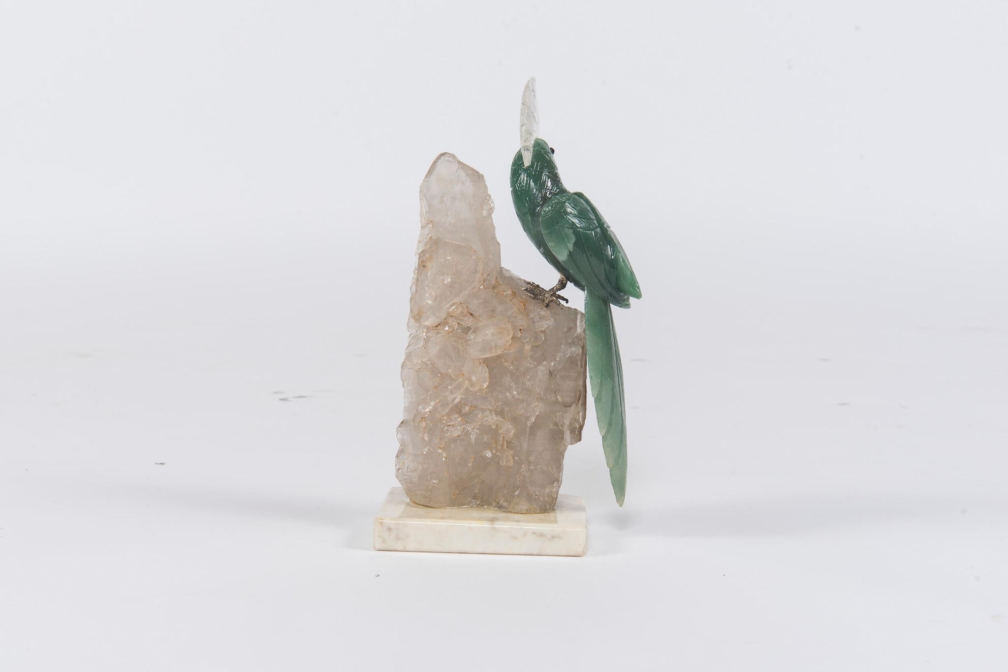 A stunning stone cockatiel mounted on a quartz specimen with white marble base. He is hand carved green calcite with a tiger eye beak and trimmed with rock quartz. An exotic bird which is brilliantly displayed by a decorative combination of
