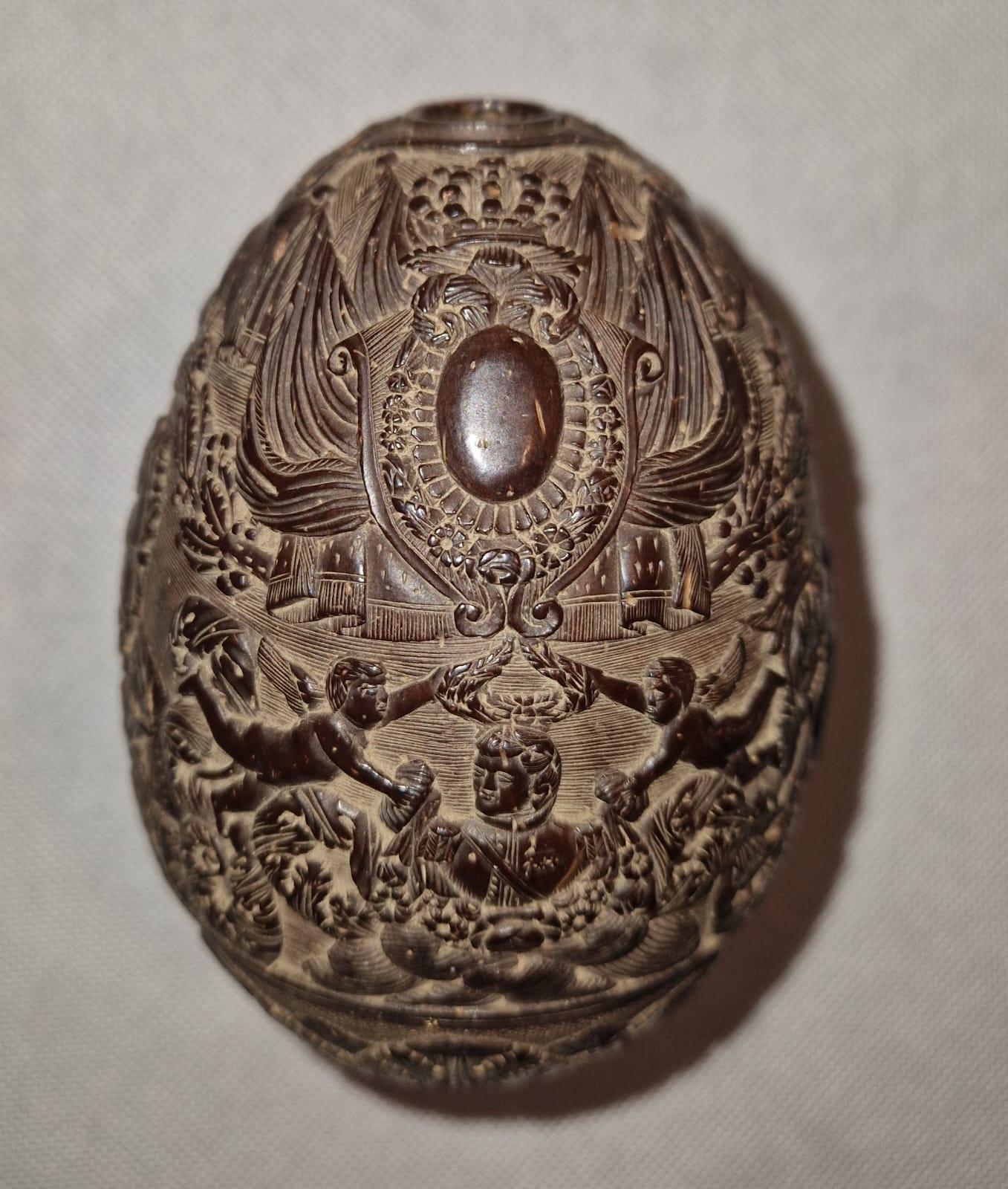 Very pretty, richly and finely carved coconut dating from the Empire period. With rotating decoration, it partly represents an admiral surrounded by two cupids holding the laurels of Victory topped with a shield adorned with flags probably those of