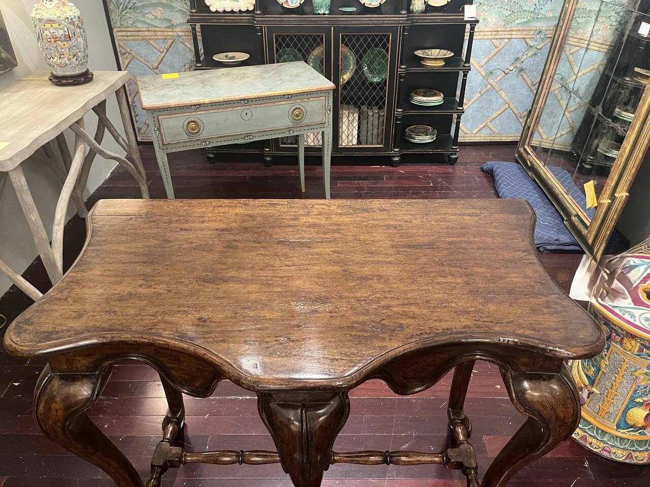 Elevate your space with our handsome Carved Console Table. Crafted with a Walnut finish, its Cabriolet legs add a hint of elegance, while the serpentine top and apron add a touch of sophistication. Intentional light distressing lends a rustic charm,