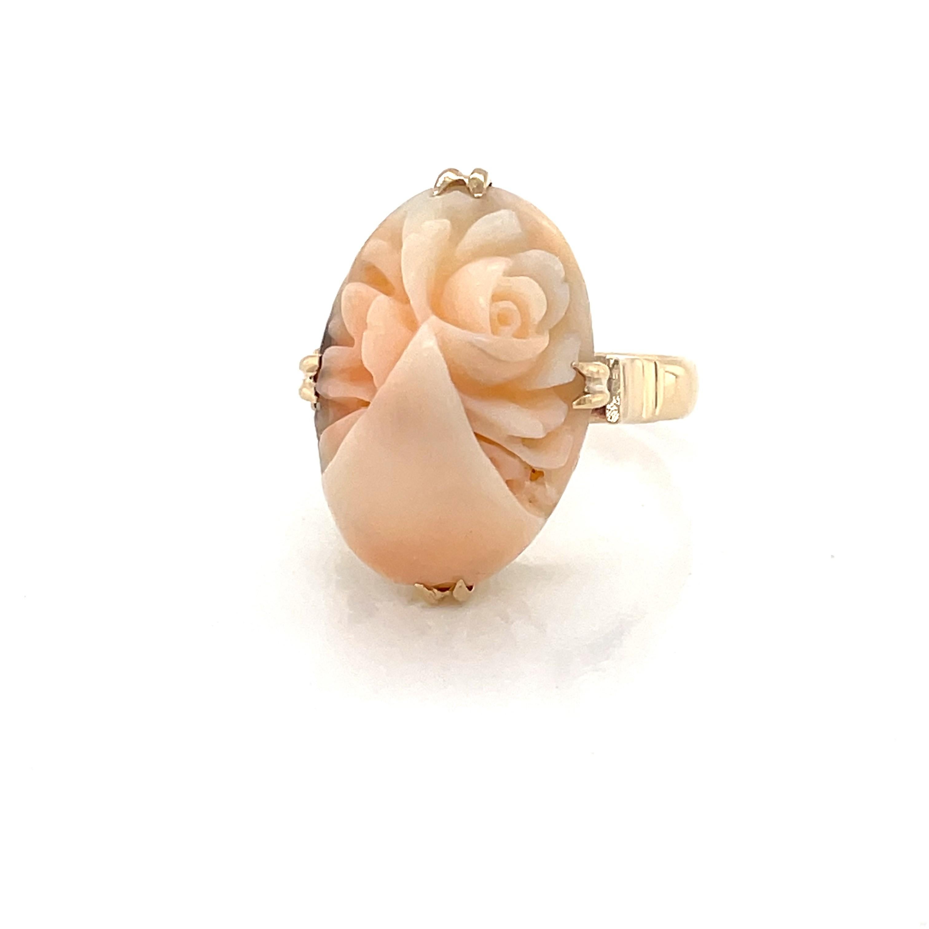 Romantic, floral inspired hand carved natural coral with light pink and white hues is featured a top the gallery of twelve karat 12K yellow gold in this antique style ring.
The beautiful oval cabochon measures approximately 12mm x 20mm  in this size