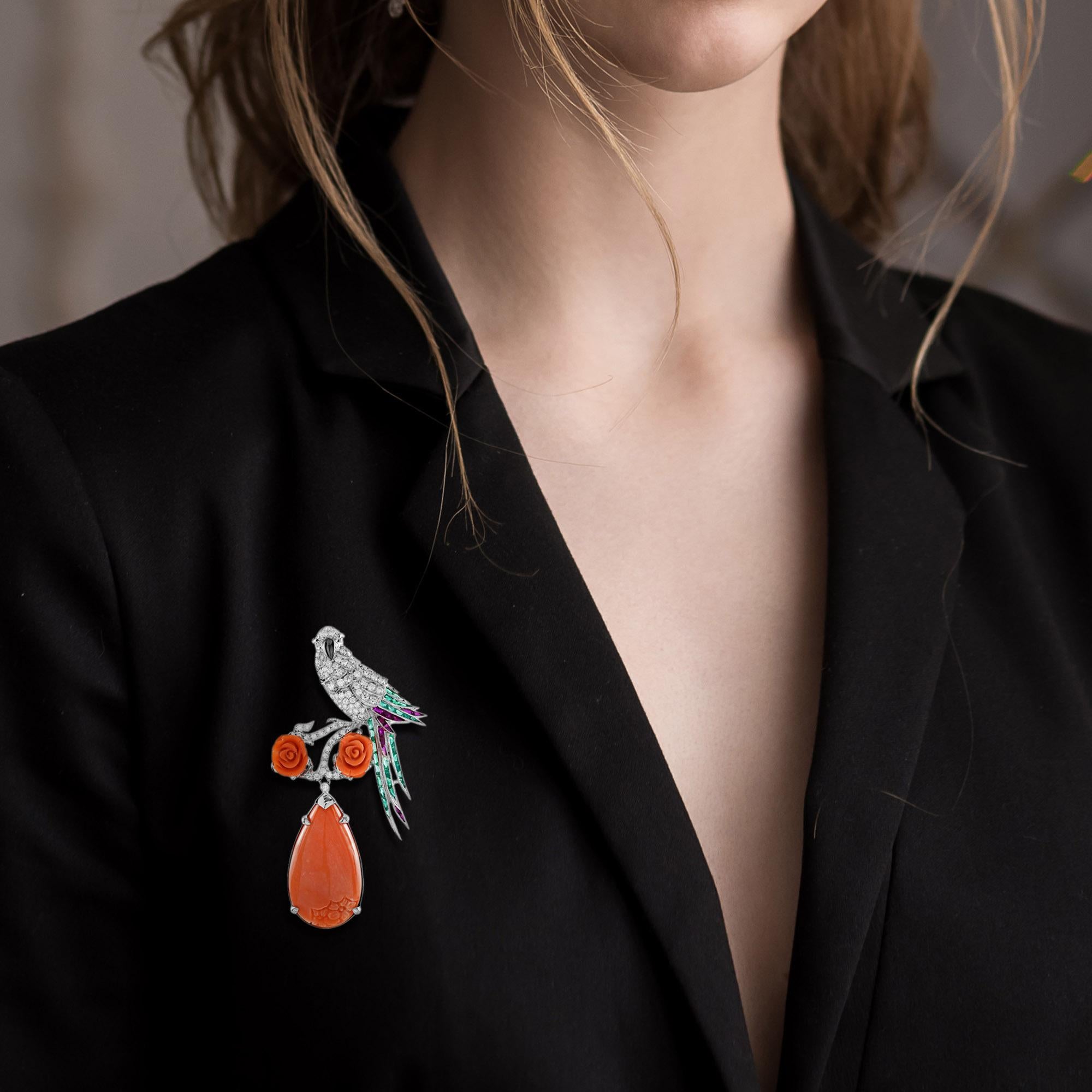 The bird brooch modeled in the form of a parrot perch upon flowers. The highlight blooming flower formed by carved corals in roses shape and drop shaped coral. The head and body features glittering eighty-one H color SI clarity diamonds while French