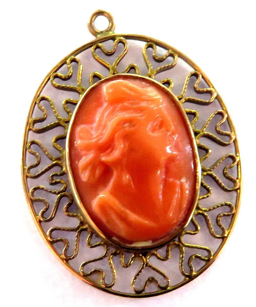This carefully carved coral woman face bezel set charm or pendant is surrounded by a beautifully designed filigree frame in 18k yellow gold. 
This charm weighs 1.7 grams
This charm measures 1 inch high by 11/16 inch wide
