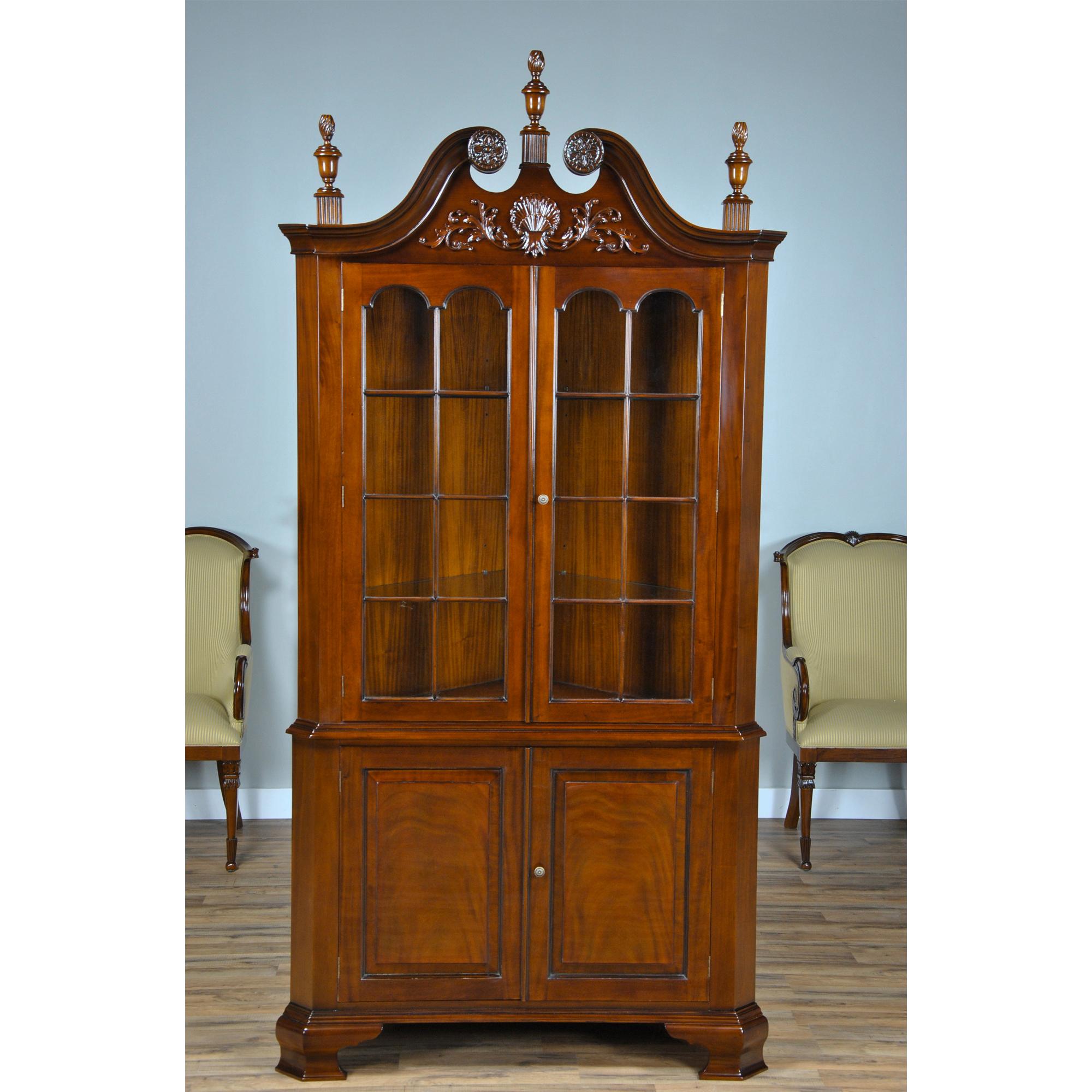 Der Carved Corner Cabinet ist ein übergroßer zweiteiliger Eckschrank mit Schnitzereien auf dem Schwanenhalsgiebel und der Oberseite des Schranks sowie auf den drei abnehmbaren Endstücken.  Der Schrank wird aus ofengetrocknetem, auf Plantagen