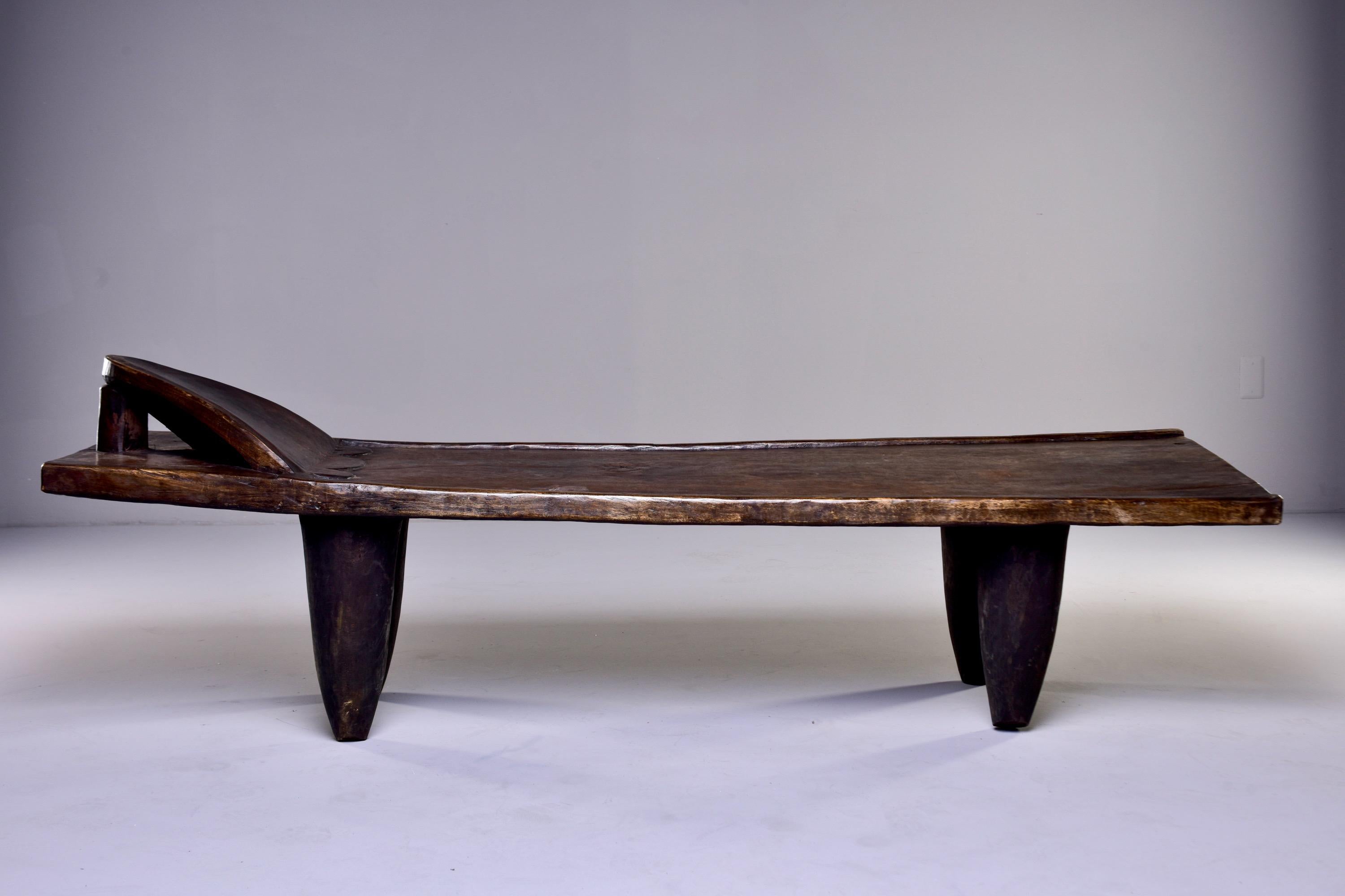 Circa 1980s wooden bench or day bed by the Senufo people of the Ivory Coast. Dark stained hand-carved wood bench has a built in head rest and thick, tapered legs.

Handcrafted by the Senufo Tribe of Northern Cote d'Ivoire.

18” high at