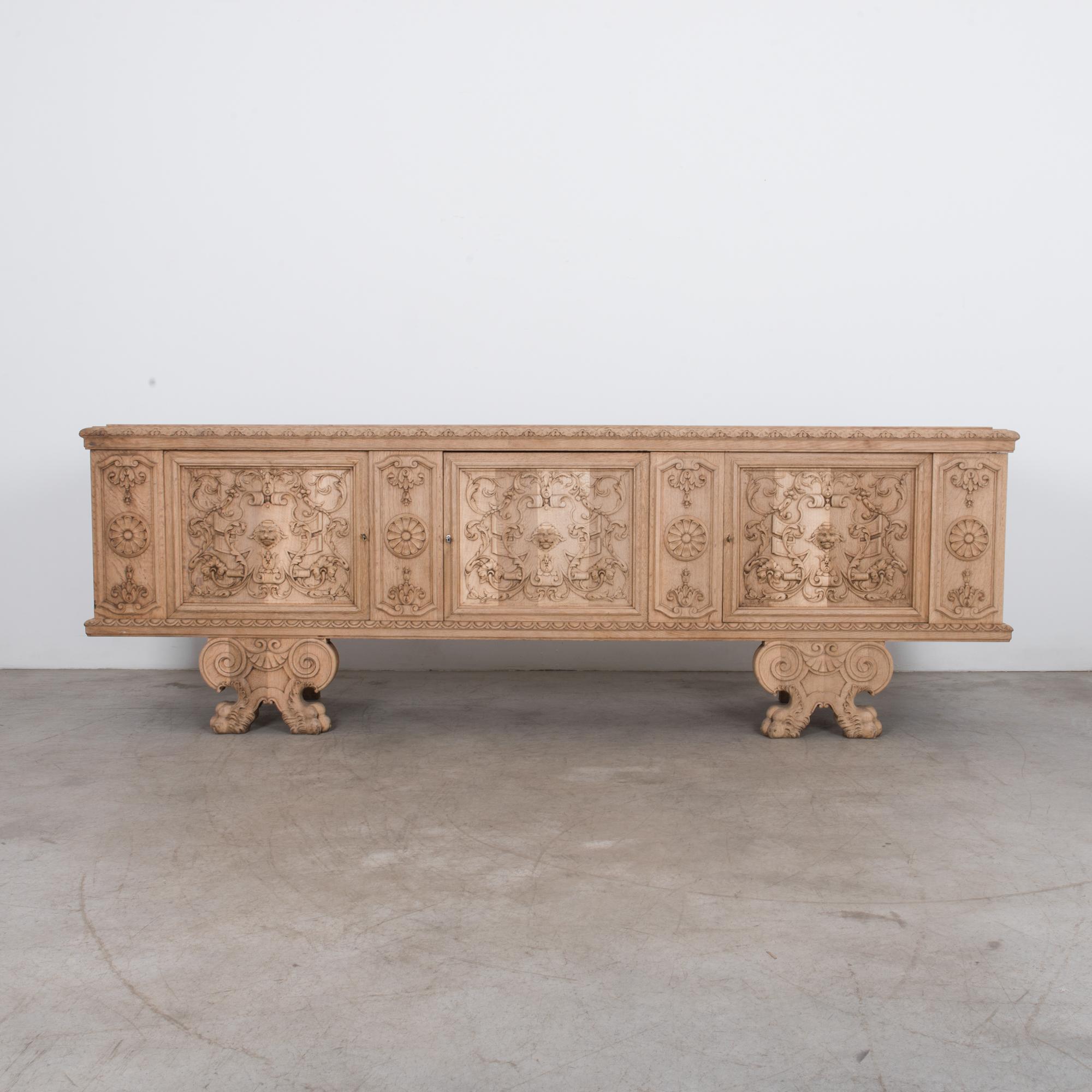 Ornate carved three-door console cabinet in oak. A clear wax finish highlights the natural wood grain. This piece great character with unique figurative carving and lion motif give. A bright and textured oak is updated for contemporary interiors,